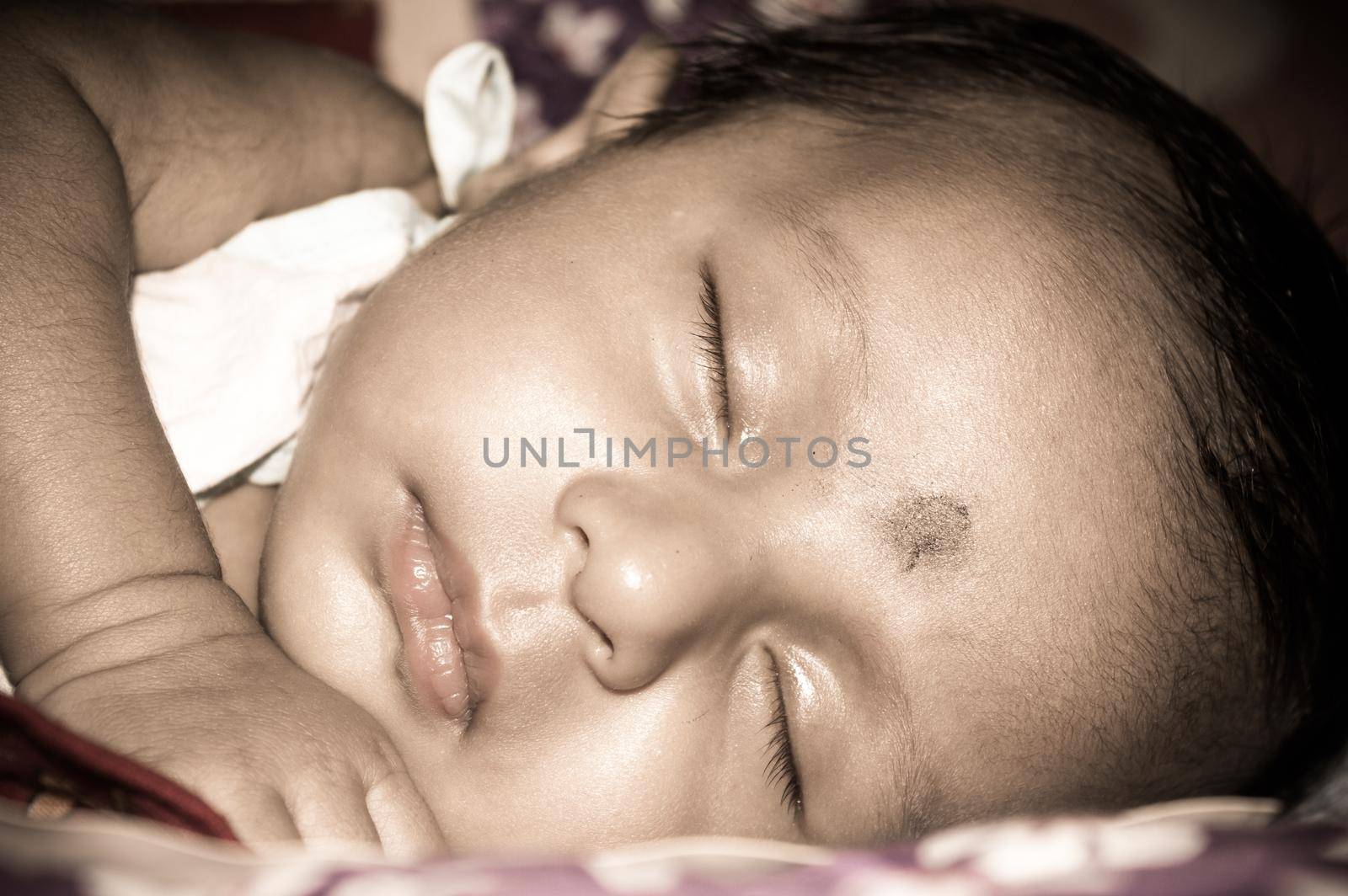 Close up face of a cute sleeping newborn baby. Closeup portrait of a Sweet just born infant boy captured in sleepy mood drowsy eyes. Hand on Chin. Front view. Child care kid background image.