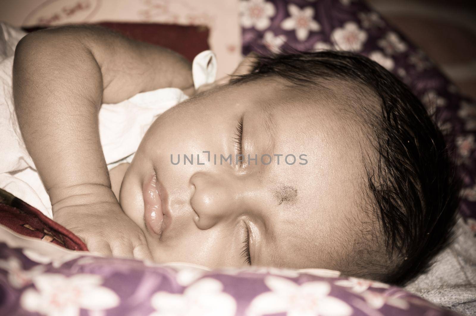 Close up face of a cute sleeping newborn baby. Closeup portrait of a Sweet just born infant boy captured in sleepy mood drowsy eyes. Hand on Chin. Front view. Child care kid background image.