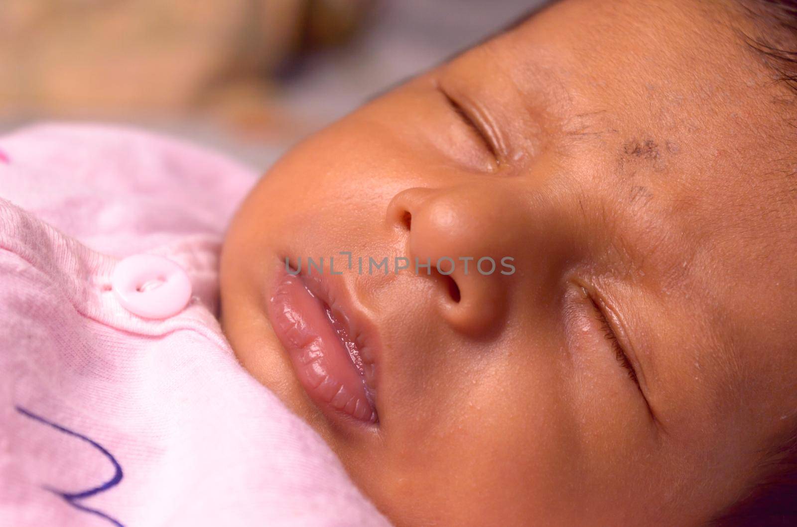 Extreme Close up face of a cute sleeping newborn baby. Closeup portrait of a Sweet One month old infant baby boy captured in sleepy mood. Front view. Child care kid background image.