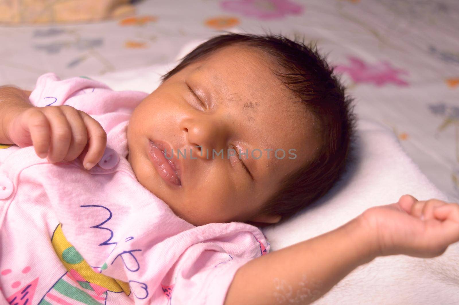 Close up face of a cute sleeping newborn baby. Closeup portrait of a Sweet One month old infant baby boy of Indian ethnicity captured in drowsy eyes with sleepy mood. Front view. Child care background