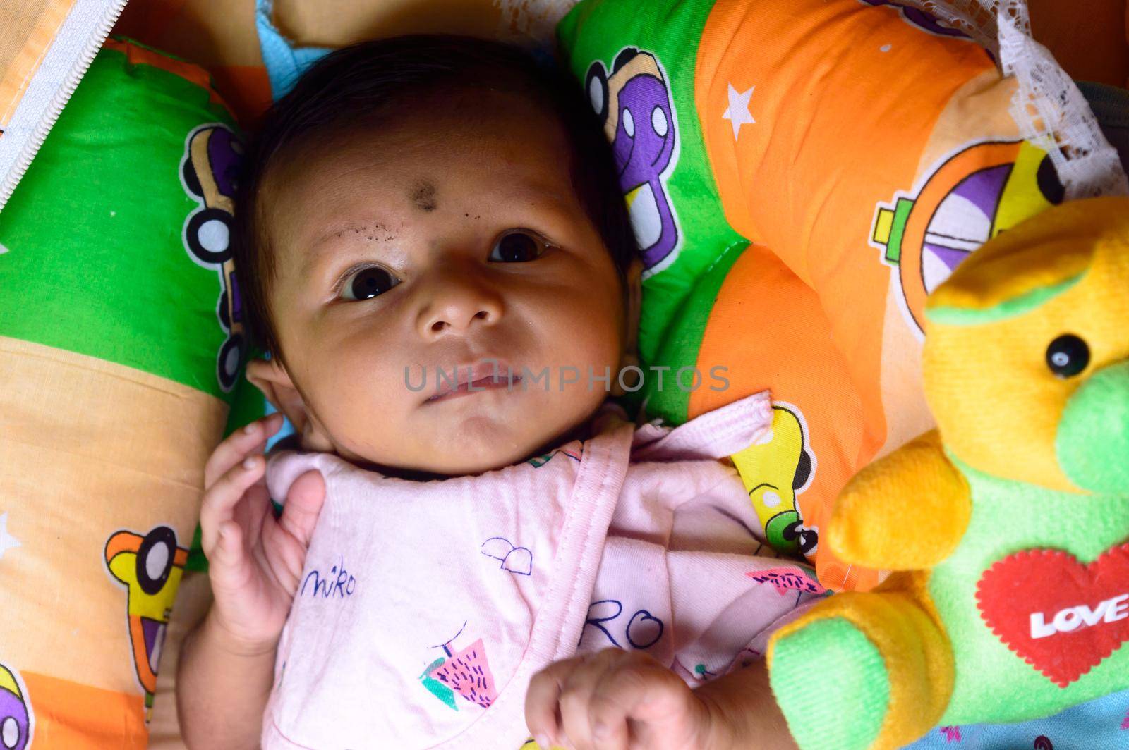 Close up portrait of cute Sweet infant toddler feeling wonder and amazed about surrounding environment. Beautiful Newborn Baby looking something unfamiliar and remarkable astonishingly. Indian ethnicity. High angel Front view. by sudiptabhowmick