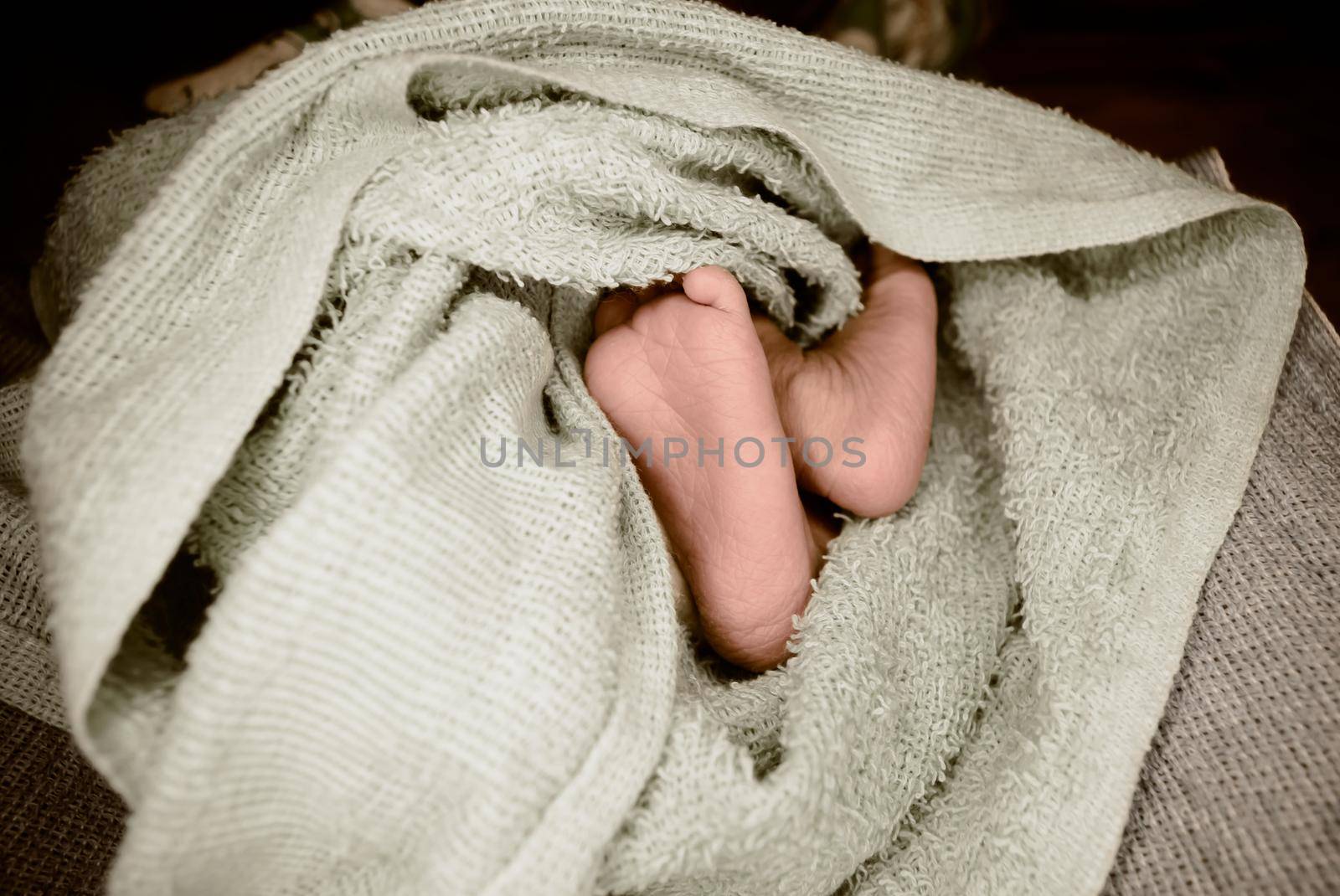 Newborn baby feet close up. The legs of a new born infant kid on a soft baby fur blanket. Cute love cozy background. Vintage color image. Copy space.