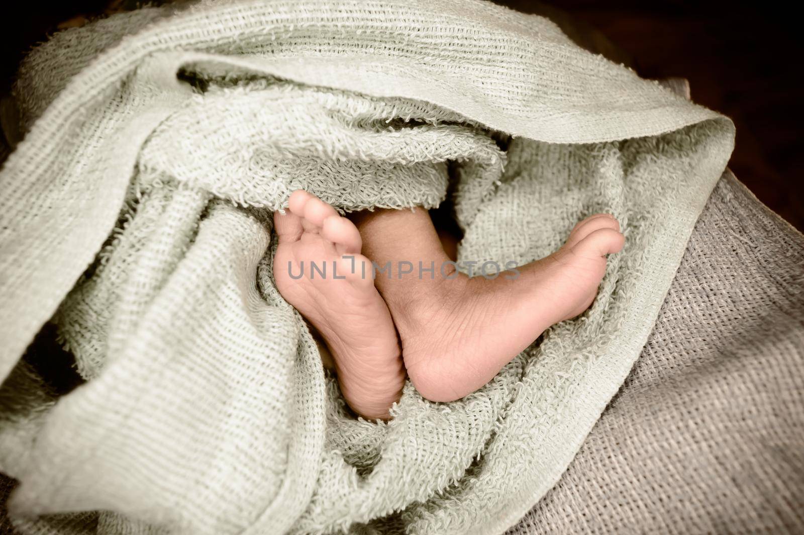 Newborn baby feet close up. The legs of a new born infant kid on a soft baby fur blanket. Cute love cozy background. Vintage color image. Copy space.