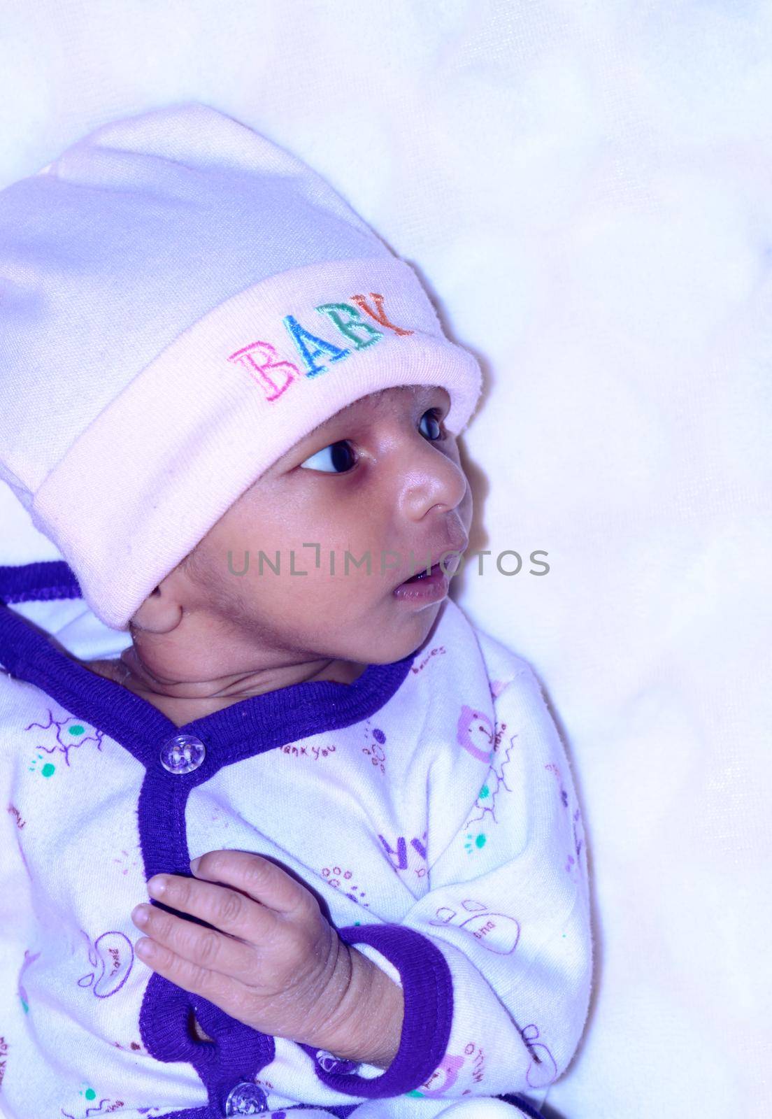 Closeup beautiful portrait of cute Indian newborn baby boy in winter clothing looking sideways feel curious and posing wonder. Sweet infant toddler isolated on white background. Copy space for text. by sudiptabhowmick