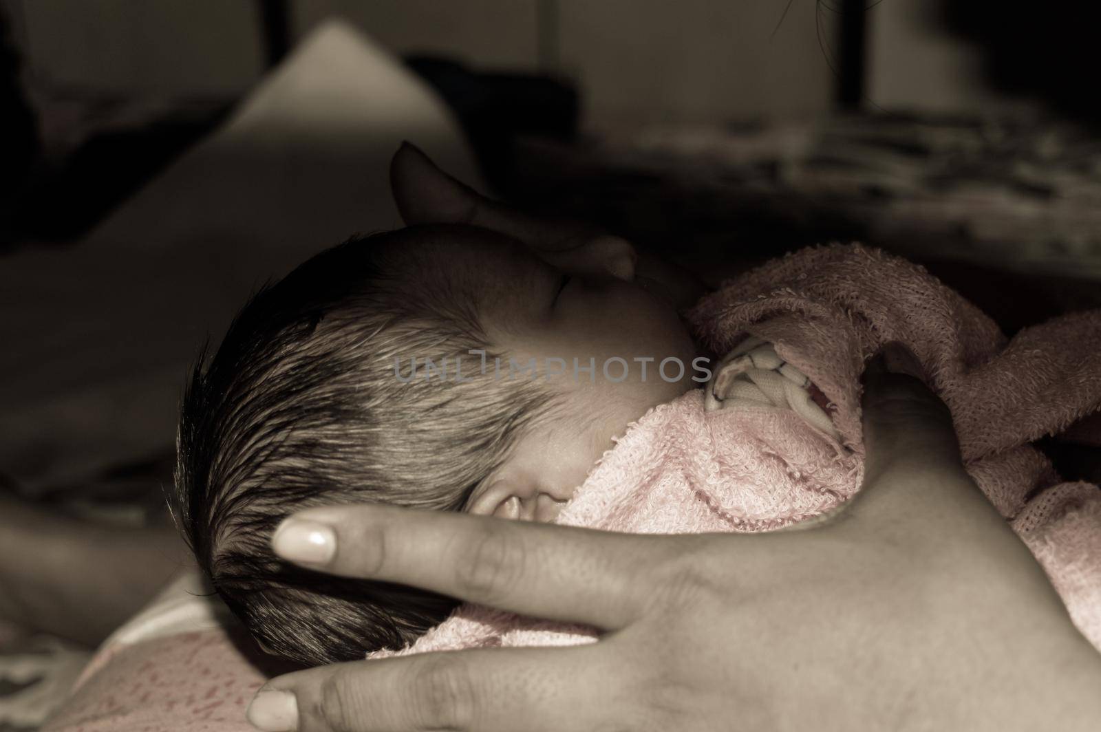 Beautiful Newborn baby boy Close up (6 days old) lying in mother lap in prenatal hospital. Kid wrapped in baby blanket (warm clothing) sleeping looking away. His mother consoling and resting her baby. by sudiptabhowmick
