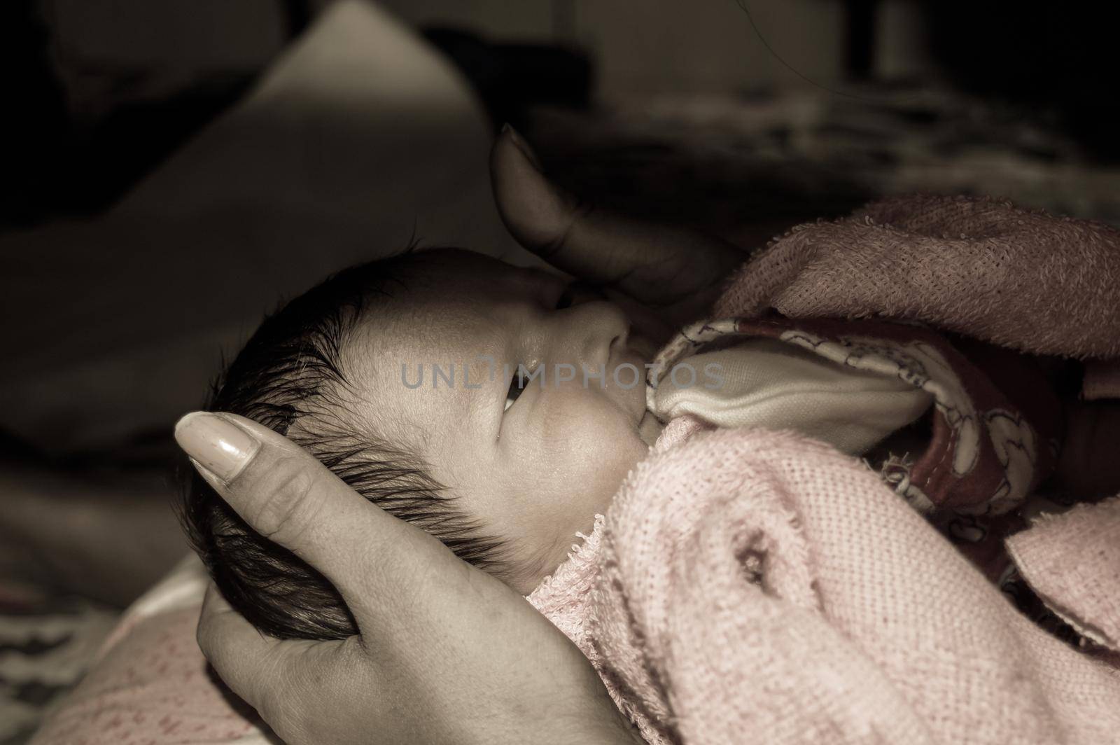 Beautiful Newborn baby boy closeup (6 days old) lying in mother lap in prenatal hospital. Kid wrapped in baby blanket (warm clothing) smiling and looking. His mother consoling and resting her baby. by sudiptabhowmick