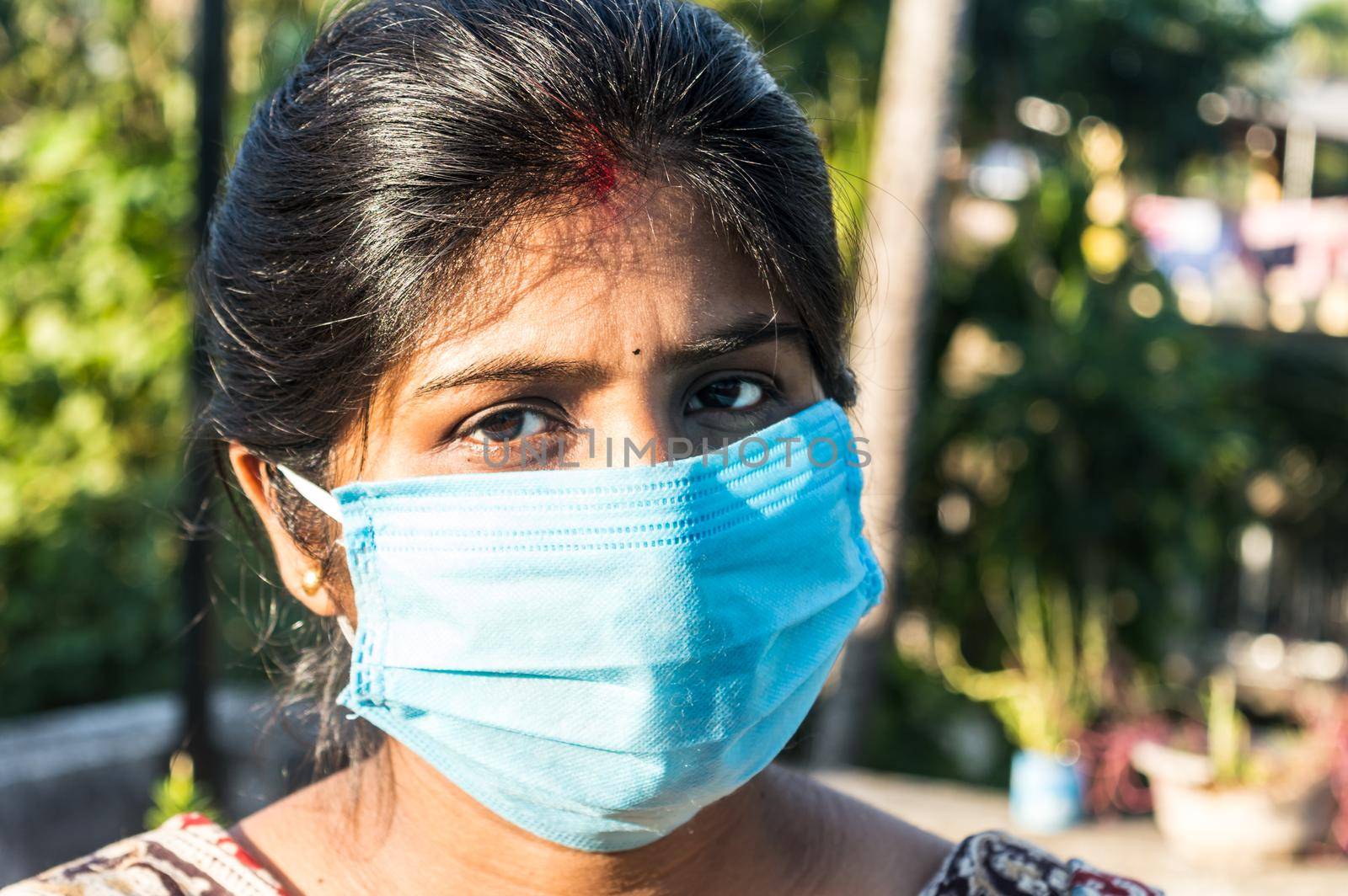 Smiling face wearing mask. Woman smiling wearing a face mask. Close up Front view of a happy Indian woman wearing a face mask smiling and looking at camera. Healthcare medicine background India. by sudiptabhowmick