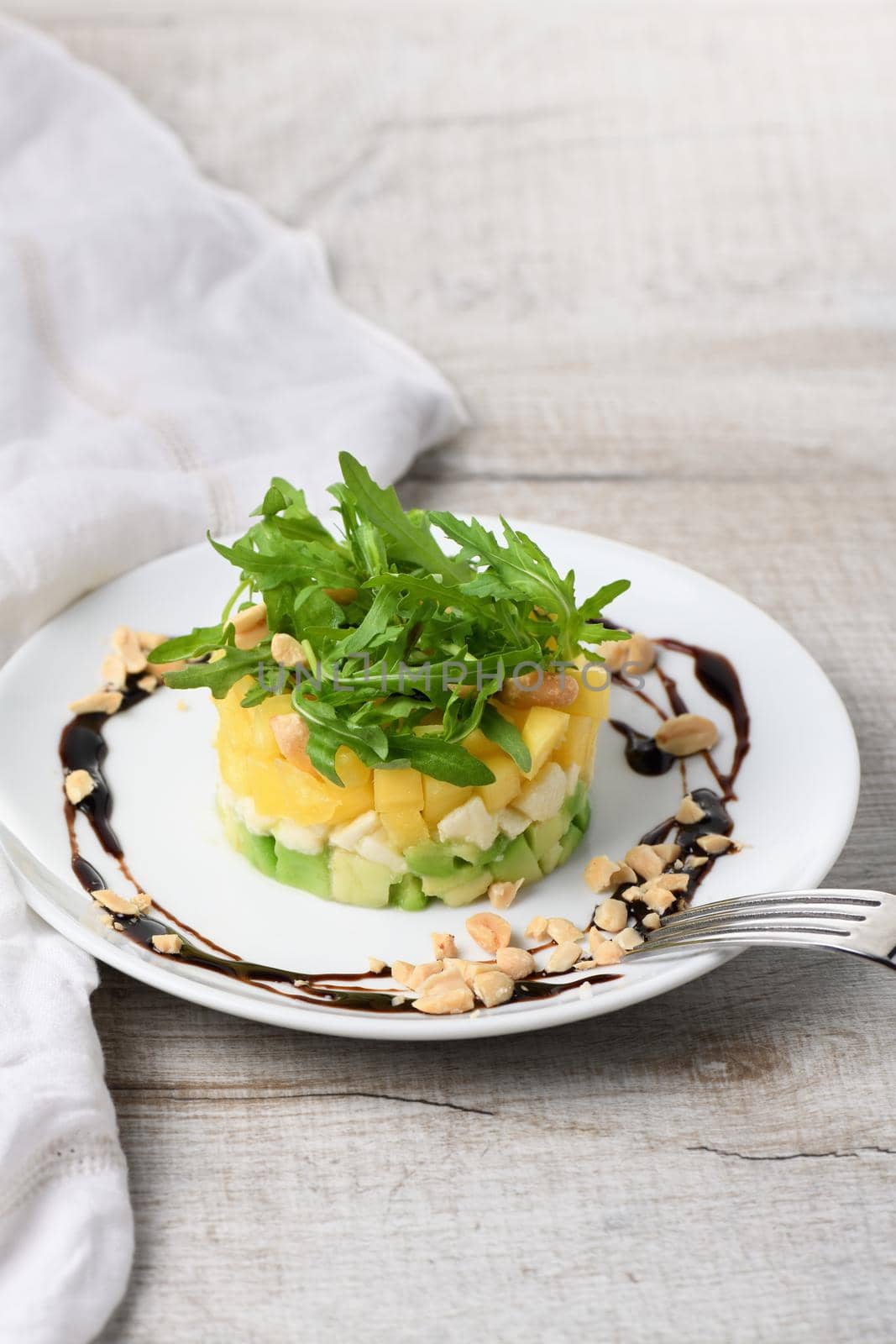 Fresh avocado, mango, mozzarella and arugula salad seasoned with nuts