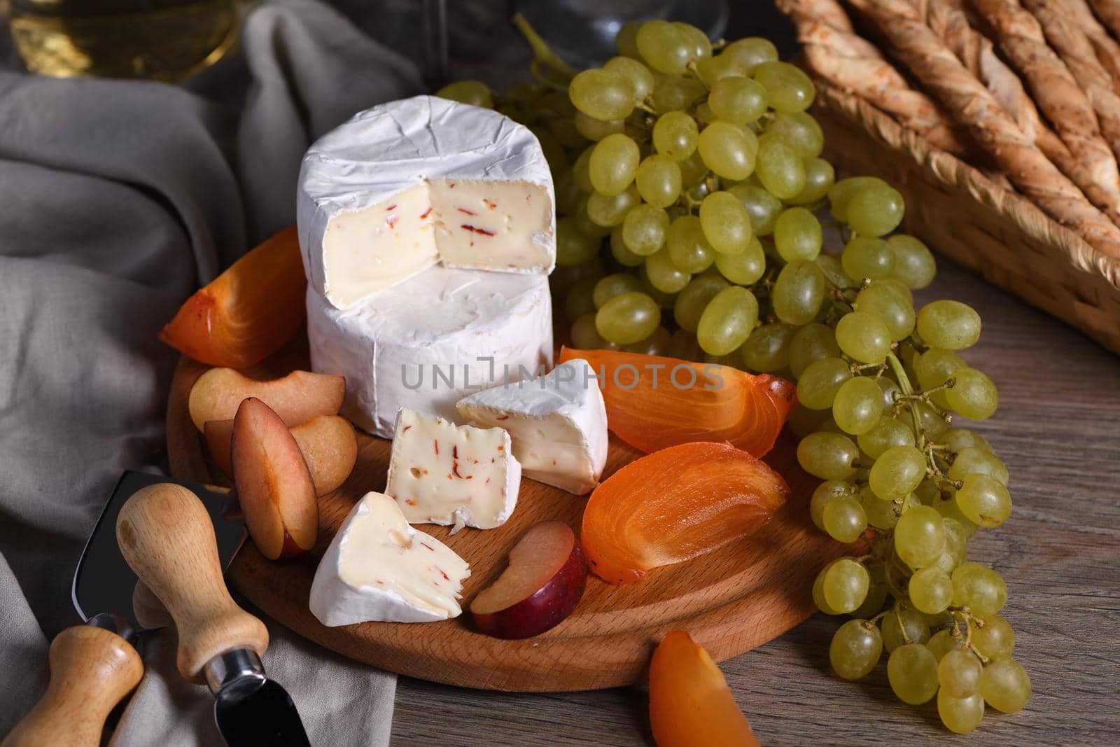 Cheese camembert with white grapes, sliced persimmons and plums, a great appetizer for wine 