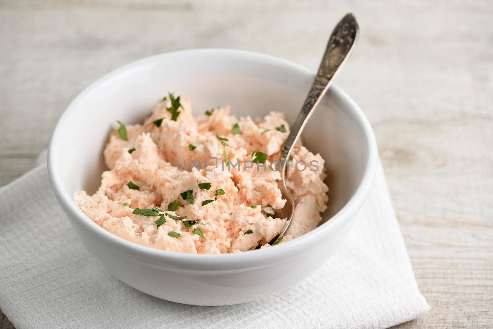 bowl of  pate  salmon with soft cheese and herb,  a textile napkin on a wooden table