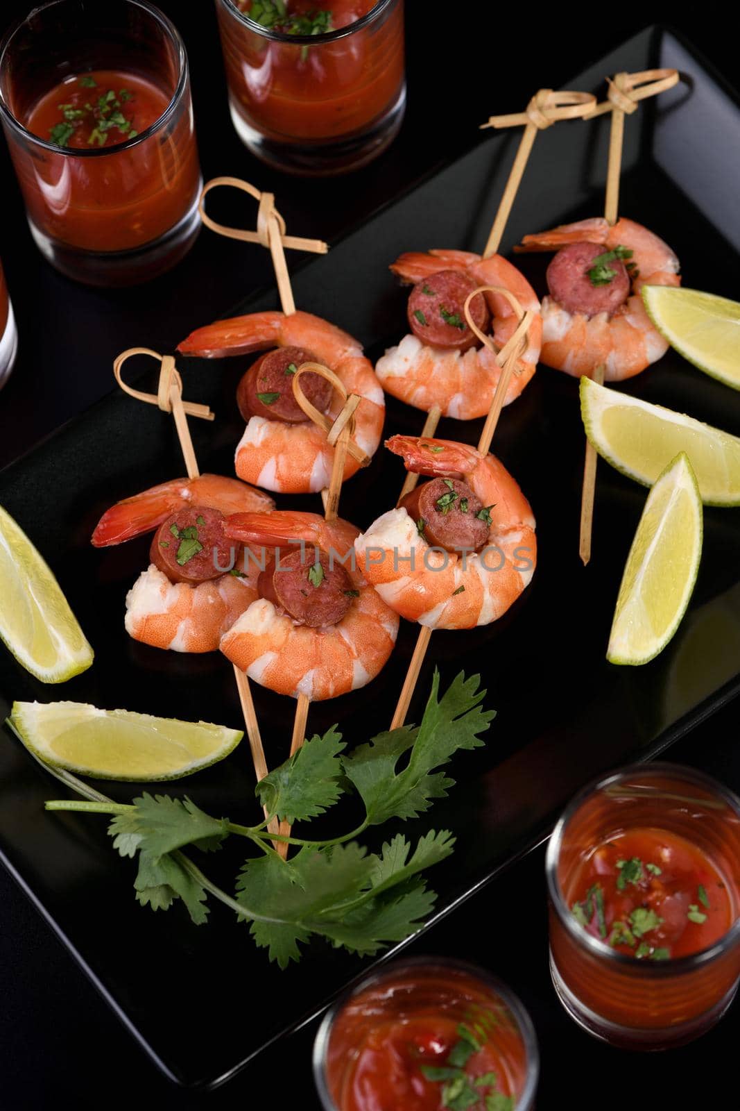 Appetizer of shish kebab with shrimps and chorizo sausages with barbecue sauce in a glass