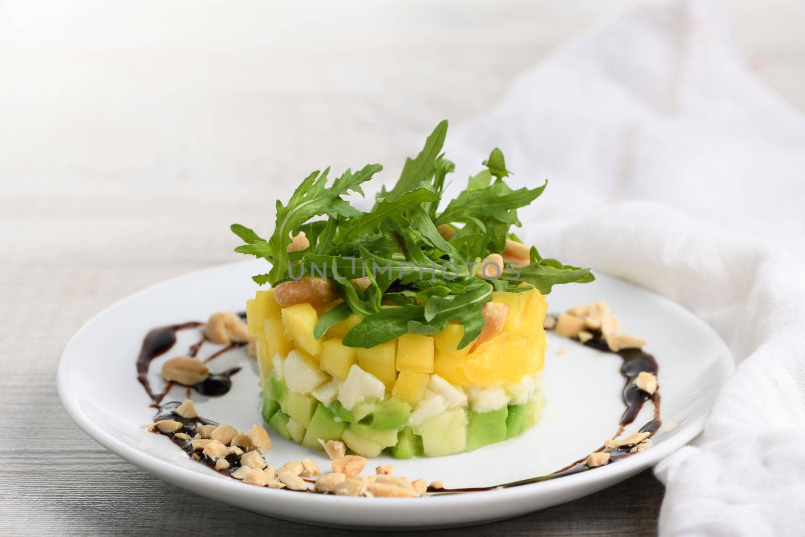 Fresh avocado, mango, mozzarella and arugula salad seasoned with nuts