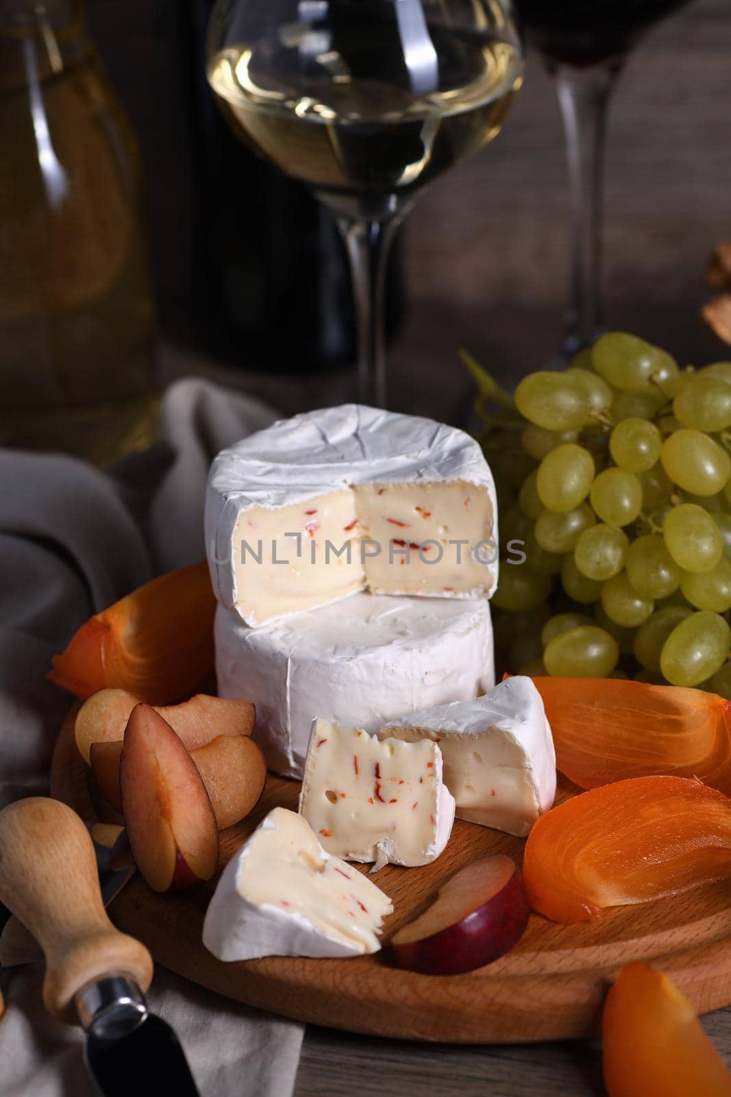 Cheese camembert with white grapes, sliced ​​persimmons and plums, a great appetizer for wine.