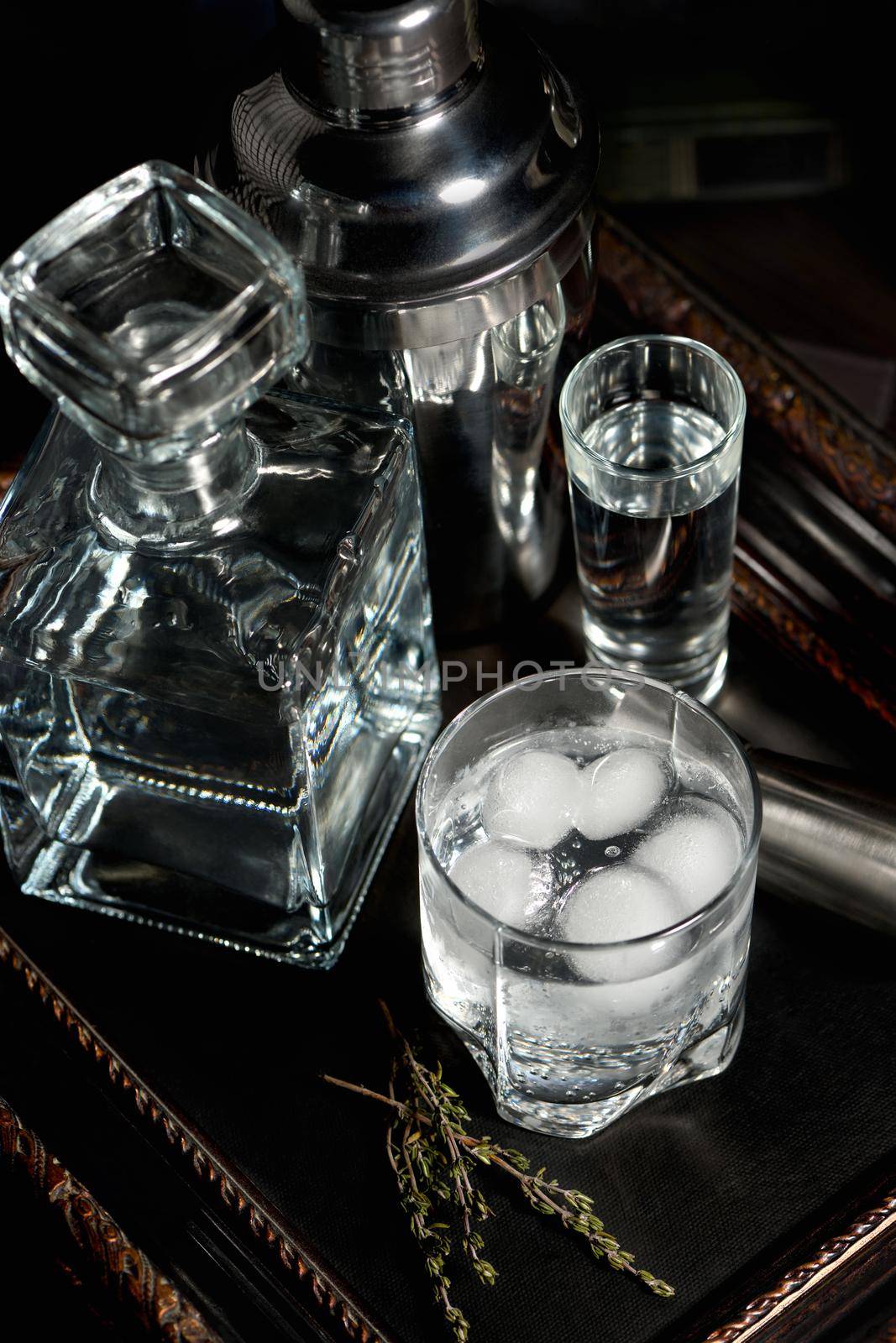 A glass of gin and tonic cooled with ice on a tray standing on the books