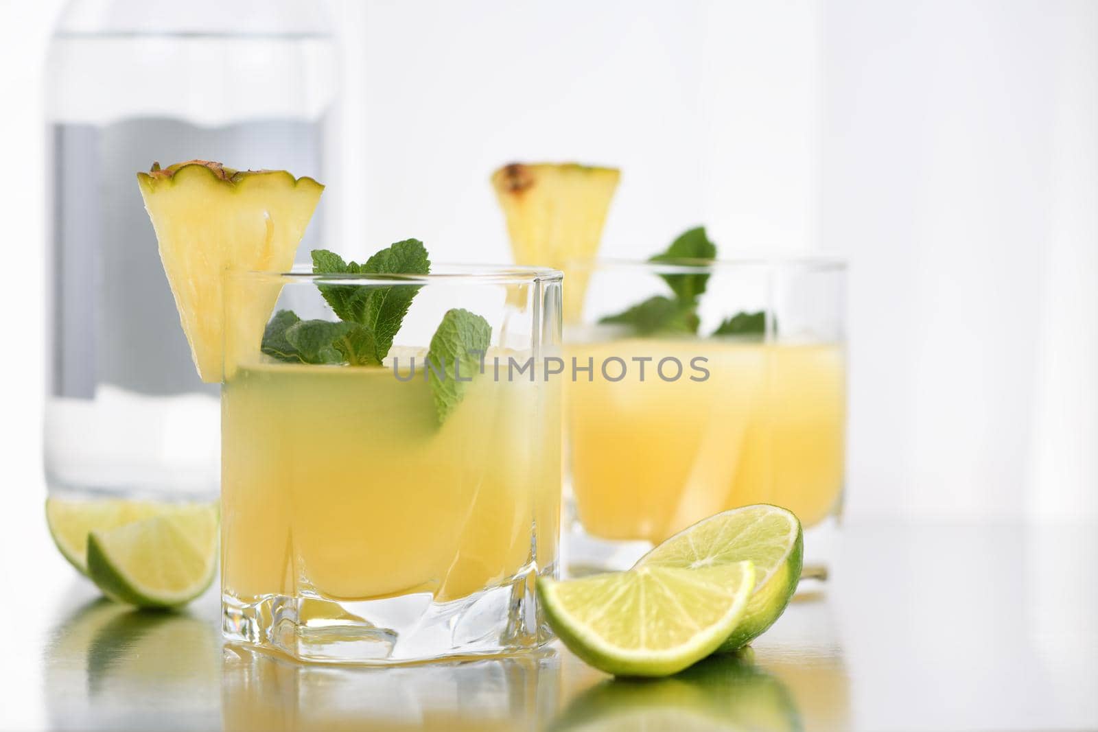 Gin cocktail with pineapple juice, a slice of lime, cooled with ice and mint