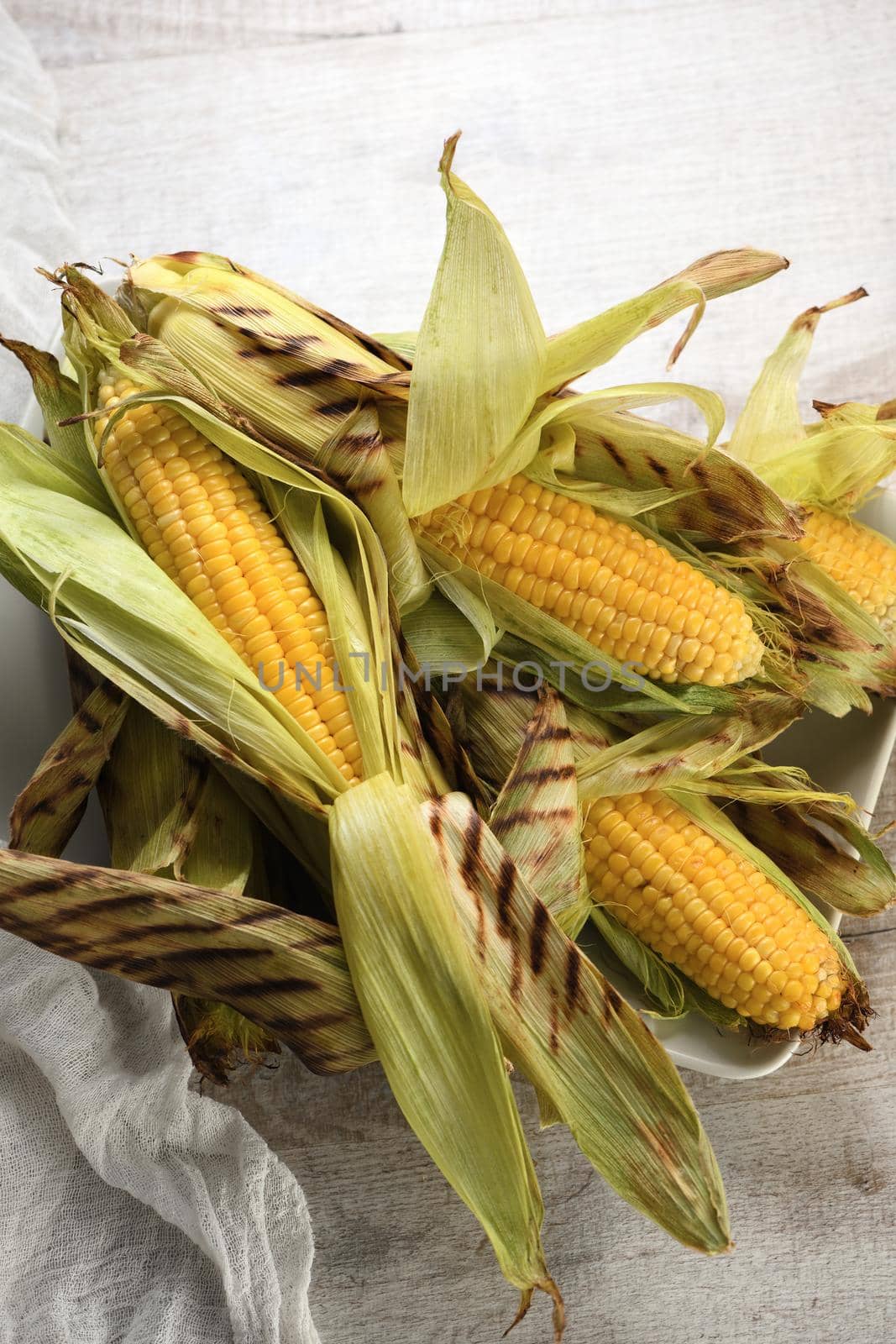 Delicate, juicy corn on the cob in husk cooked grilled