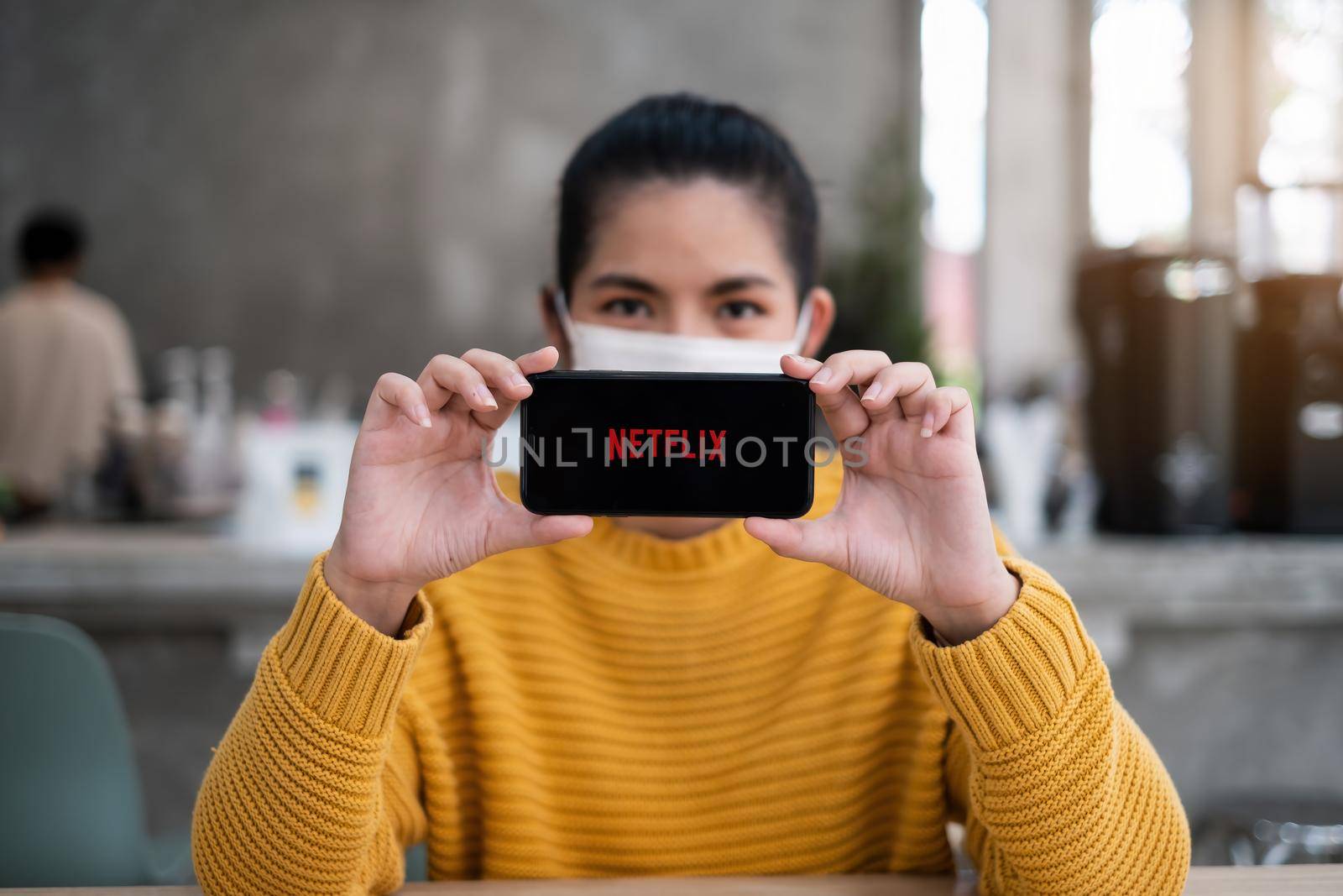 CHIANG MAI, THAILAND APR 14 2021 : Hand holding Apple iPhone with Netflix logo on a screen. Netflix is a global provider of streaming movies and TV series. by itchaznong