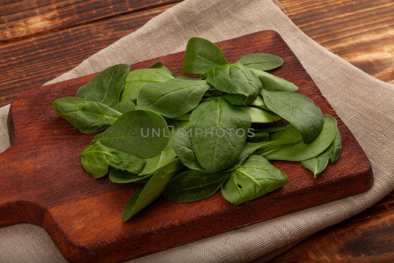 Heap of fresh green spinach on the wooden board