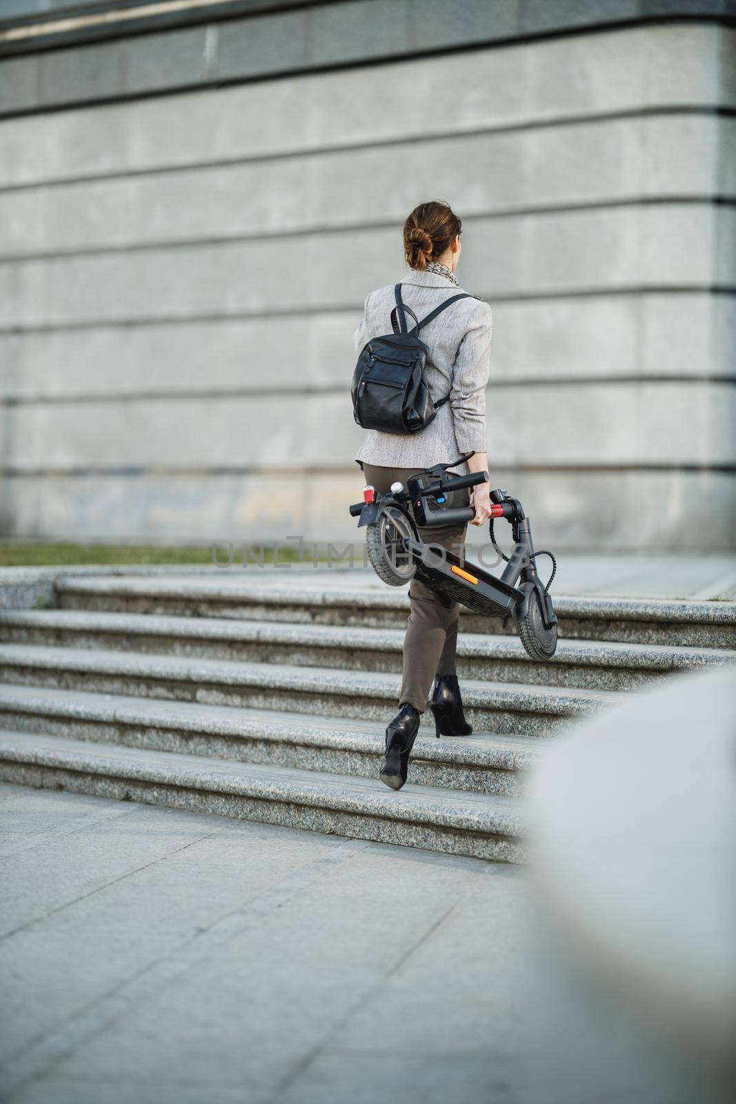 A young businesswoman going to work with an electric push scooter.