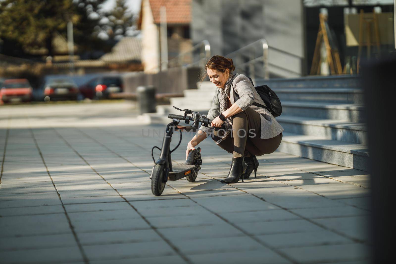 A young businesswoman going to work with an electric push scooter.