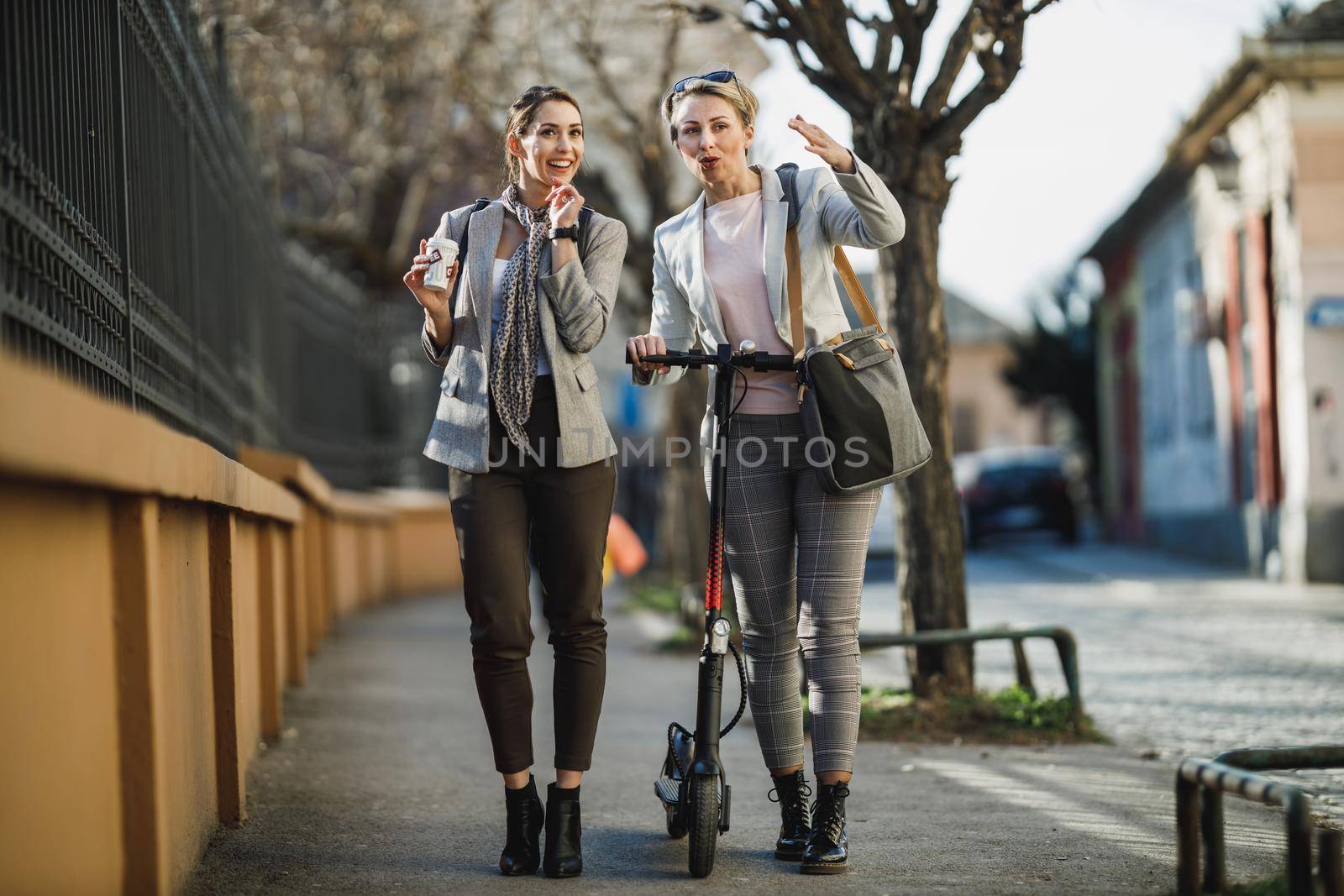 A two successful businesswomen having a quick break and chatting while walking through the city.