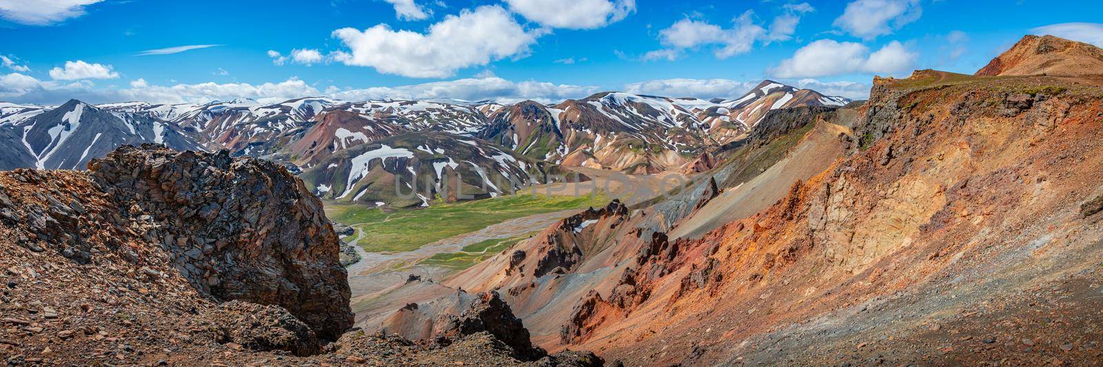 Panoramic amazing Icelandic landscape of colorful rainbow volcanic Landmannalaugar mountains, volcanic craters at famous Laugavegur hiking trail with rare blue sky, and red volcano soil in Iceland