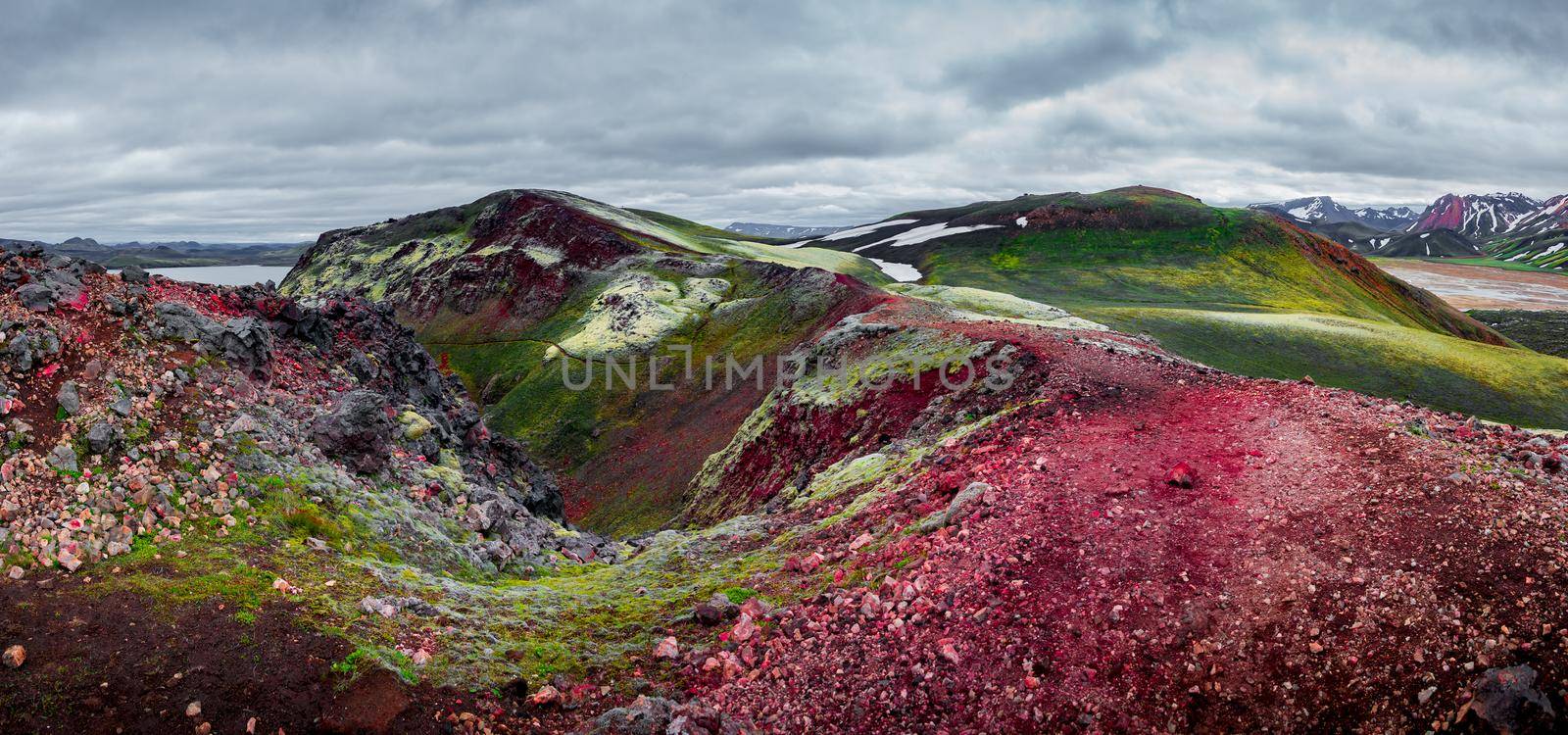 Panoramic surreal Icelandic landscape of colorful rainbow volcanic Landmannalaugar mountains, volcanic craters at famous Laugavegur hiking trail with dramatic sky, and pink volcano soil in Iceland