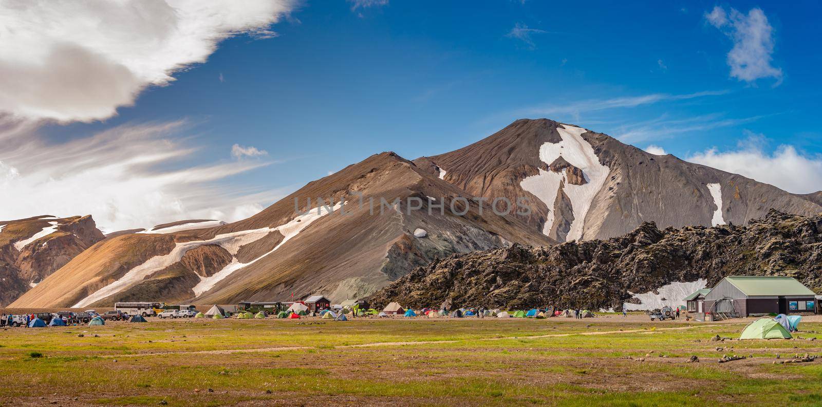 Panoramic surreal magic Icelandic landscape of colorful rainbow volcanic Landmannalaugar mountains, and a biggest camping site there with tourists and hikers, Iceland