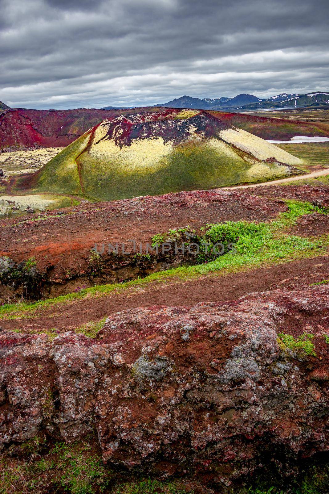 Surreal magic Icelandic landscape of colorful rainbow volcanic Landmannalaugar mountains, red and pink volcanic crater Stutur at famous Laugavegur hiking trail with dramatic sky, Iceland. by neurobite