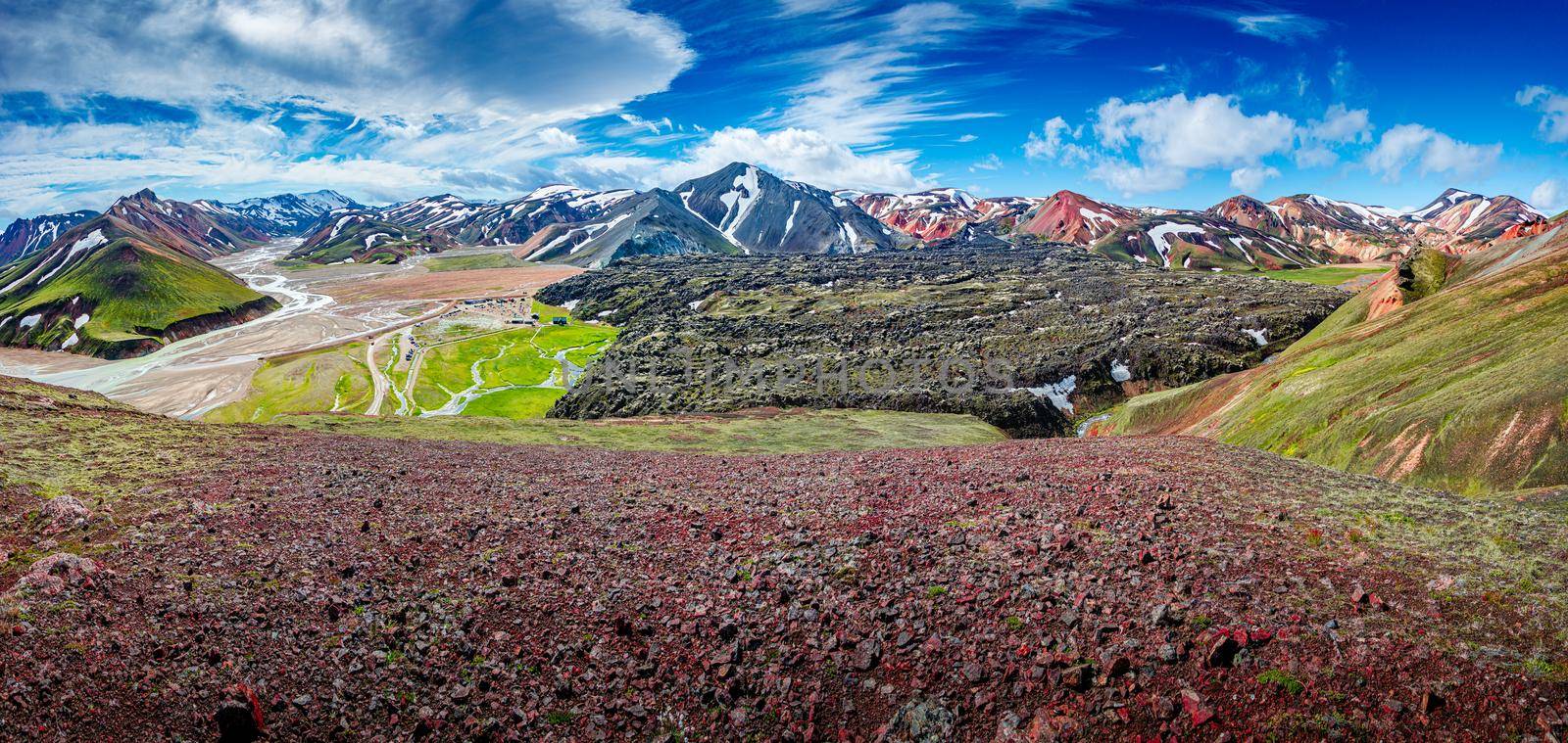 Panoramic landscape view over camping site in colorful rainbow volcanic Landmannalaugar mountains and famous Laugavegur hiking trail, with dramatic sky and snow in Iceland, summer