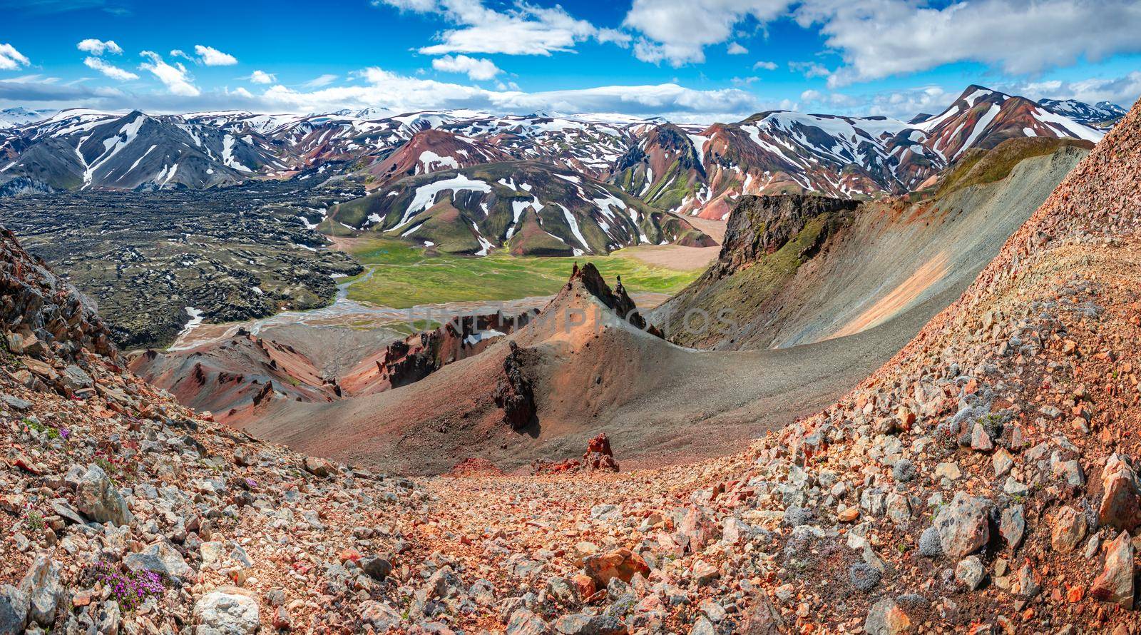 Panoramic landscape view of colorful rainbow volcanic Landmannalaugar mountains and famous Laugavegur hiking trail, with dramatic sky and snow in Iceland