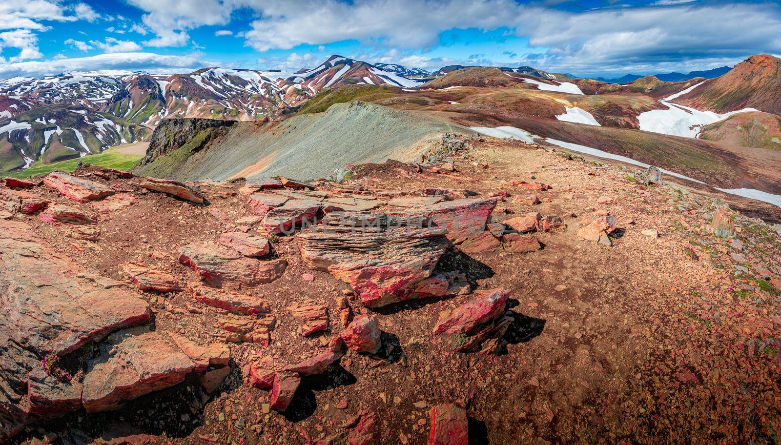 Panoramic landscape view of colorful rainbow volcanic Landmannalaugar mountains and famous Laugavegur hiking trail, with dramatic sky and snow in Iceland