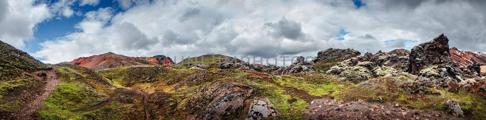 Panoramic view of colorful volcanic Landmannalaugar mountains, camping site and trail path at dramatic sky in Iceland