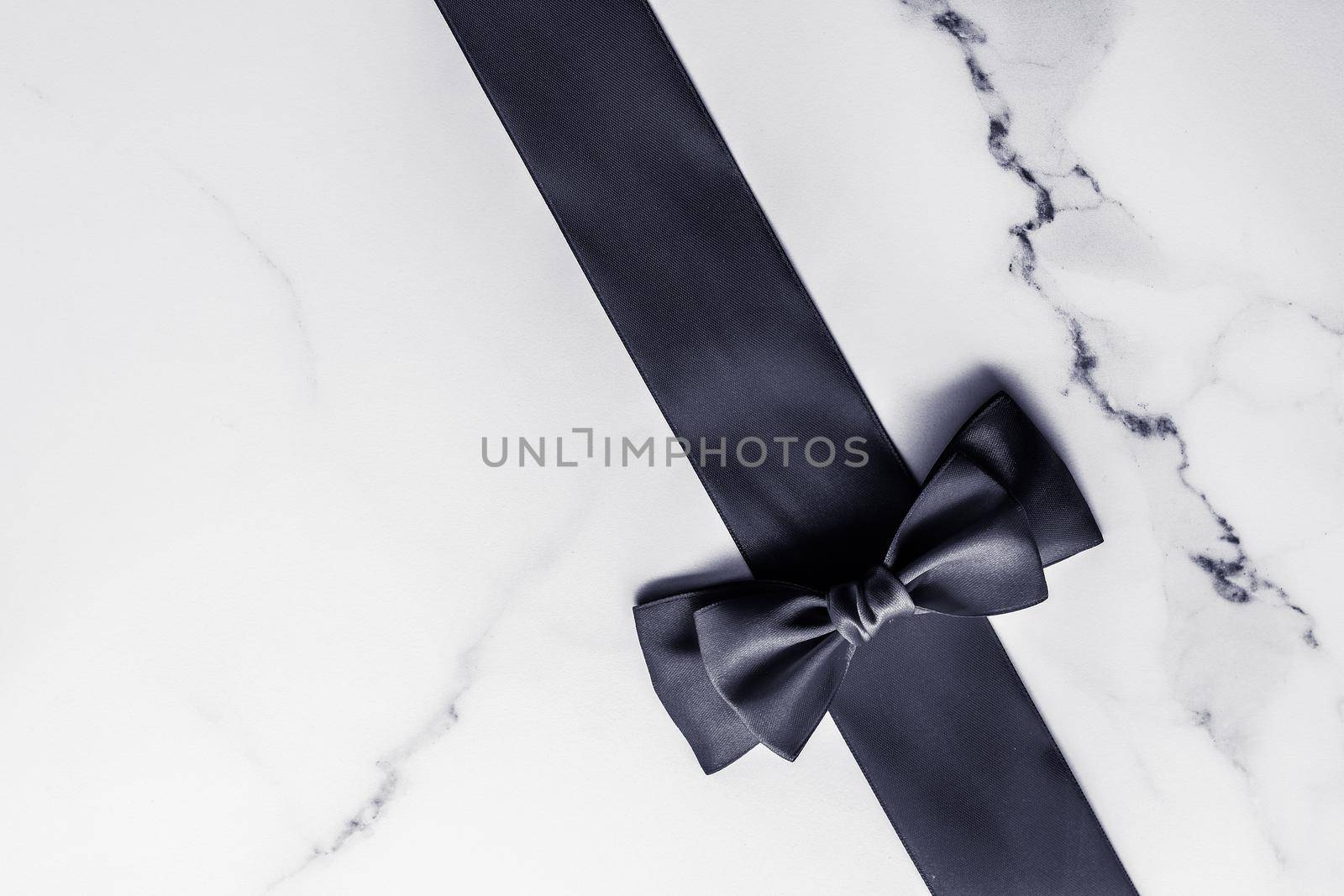 Holiday gift, decoration and sale promotion concept - Black silk ribbon and bow on marble background, flatlay