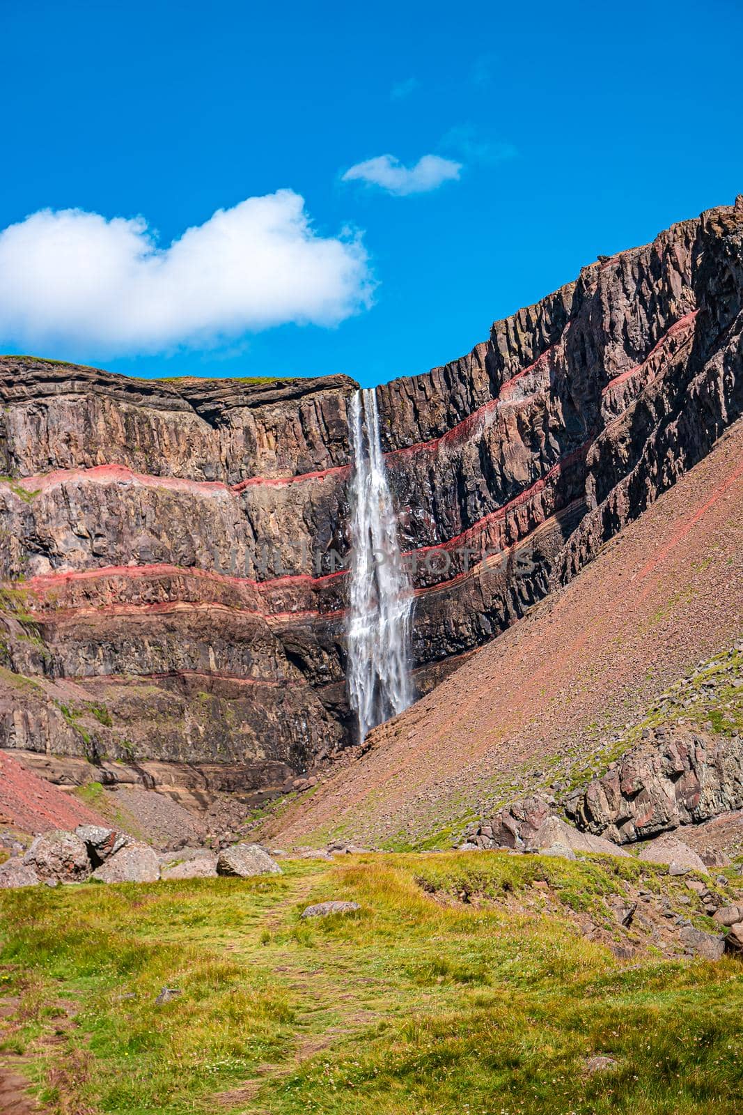 Beautiful and tall Icelandic waterfall Hengifoss and hiking trail to it, Iceland, summer, sunny day, blue sky by neurobite