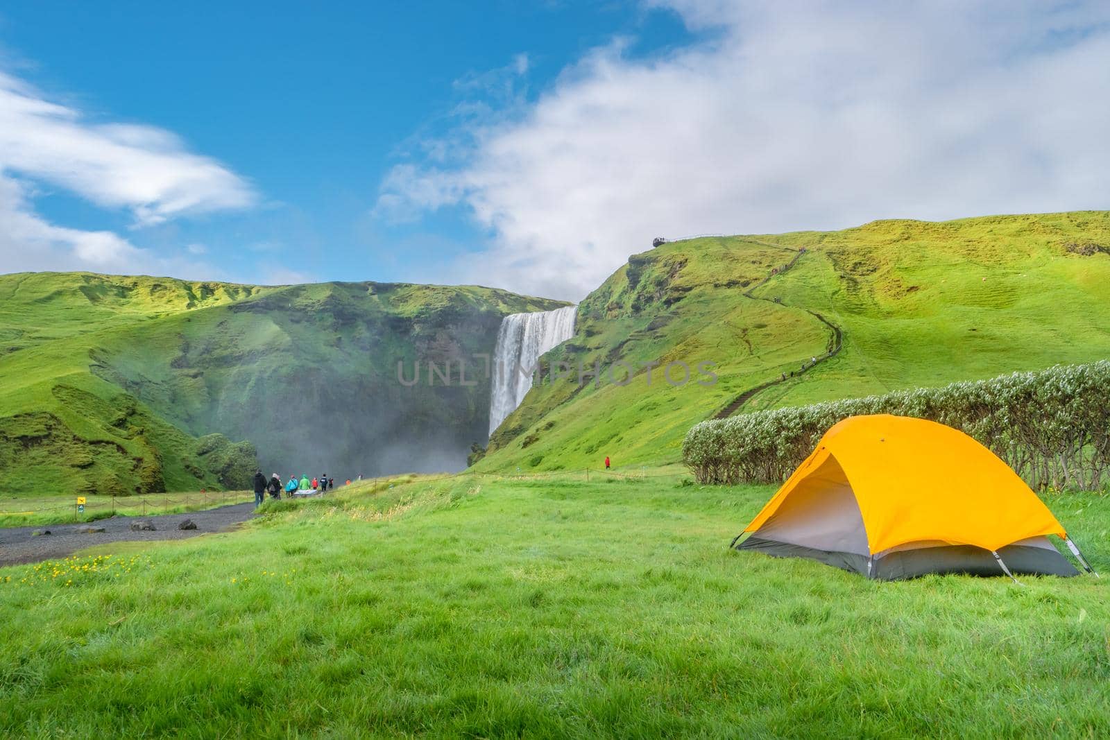 Camping site with tents in front of famous Skogarfoss waterfall, while hiking in Iceland, summer, scenic view