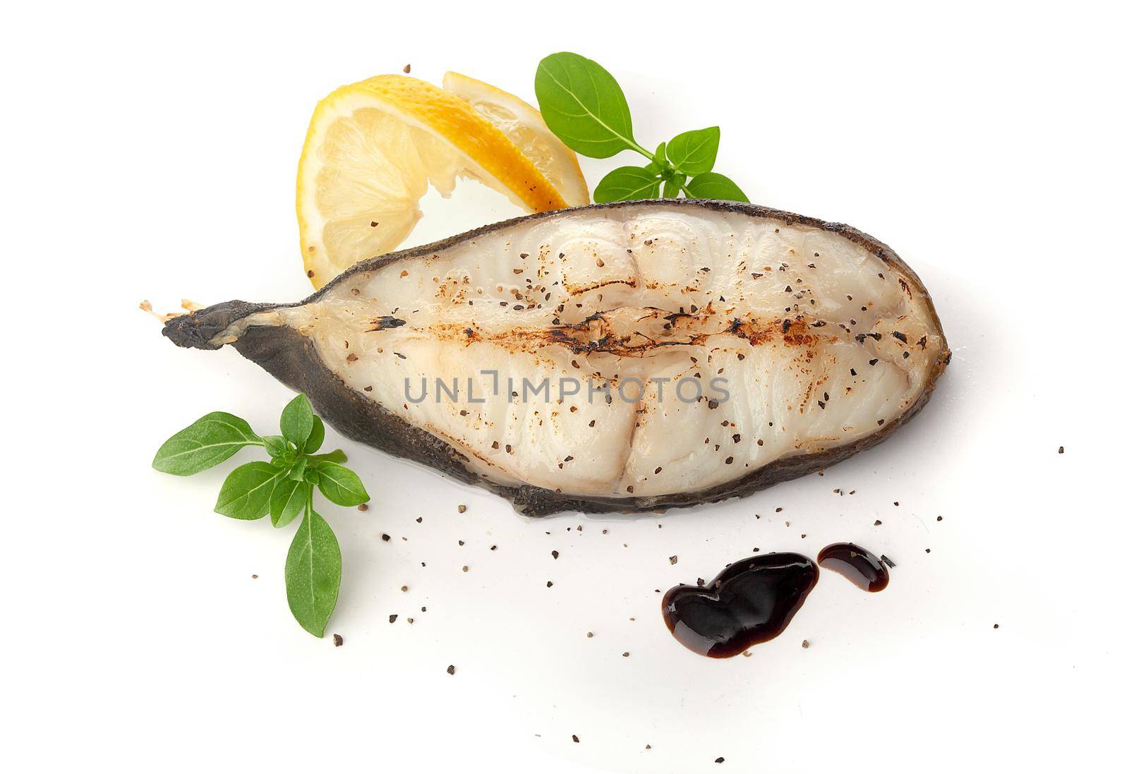 Isolated roasted catfish steak with basil, lemon and balsamic sauce