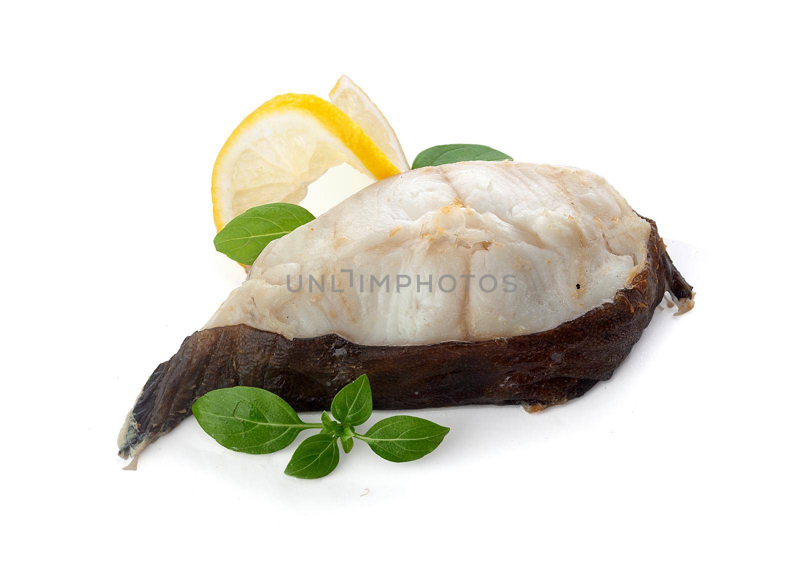 Isolated baked catfish steak with basil and lemon