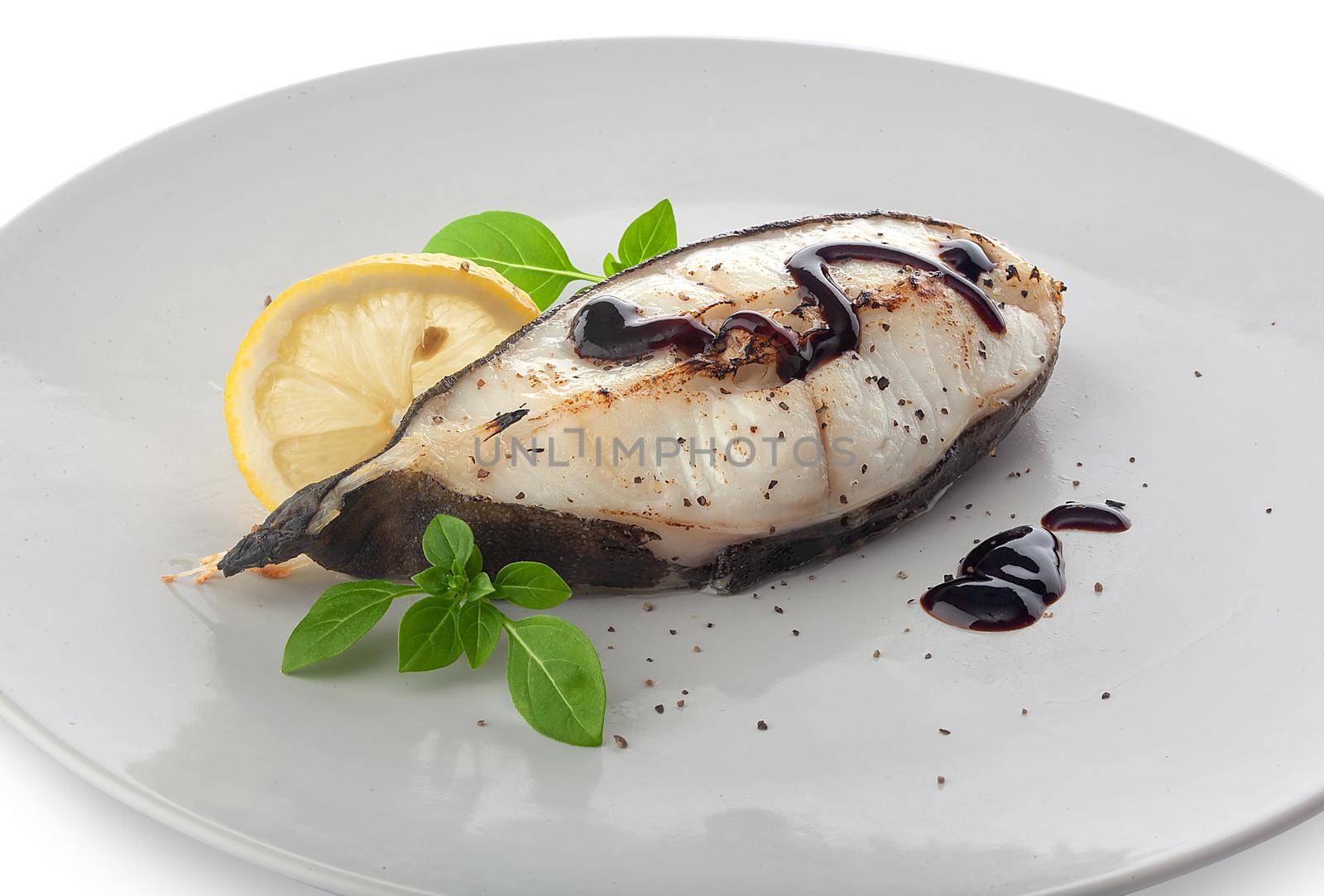 Roasted catfish steak with basil, lemon and balsamic sauce on the plate
