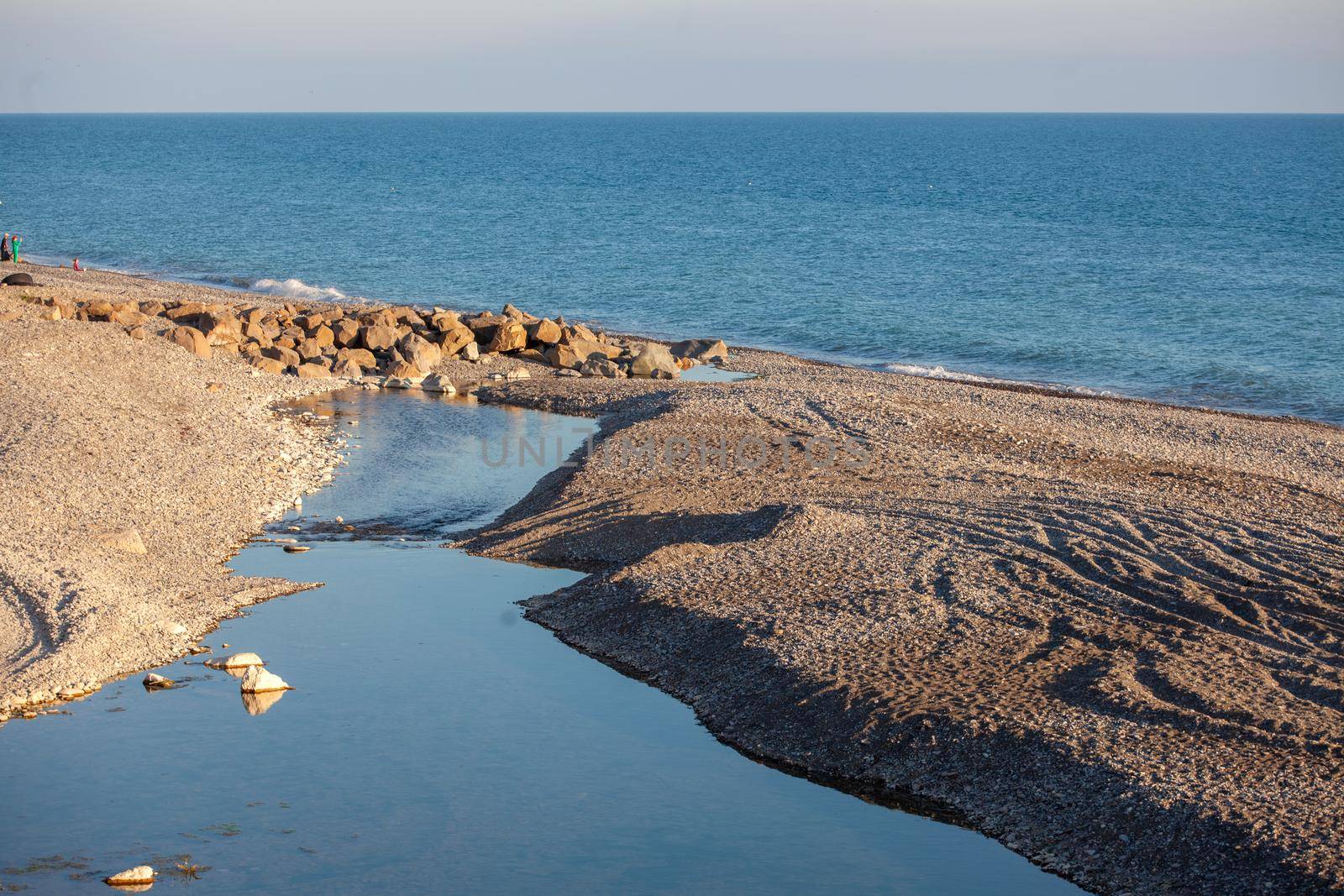 Landscape with small mountain river flows into the sea