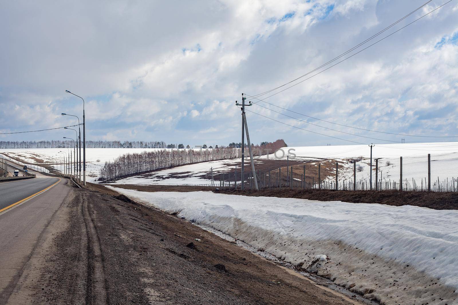 Road in the snowy field in early spring