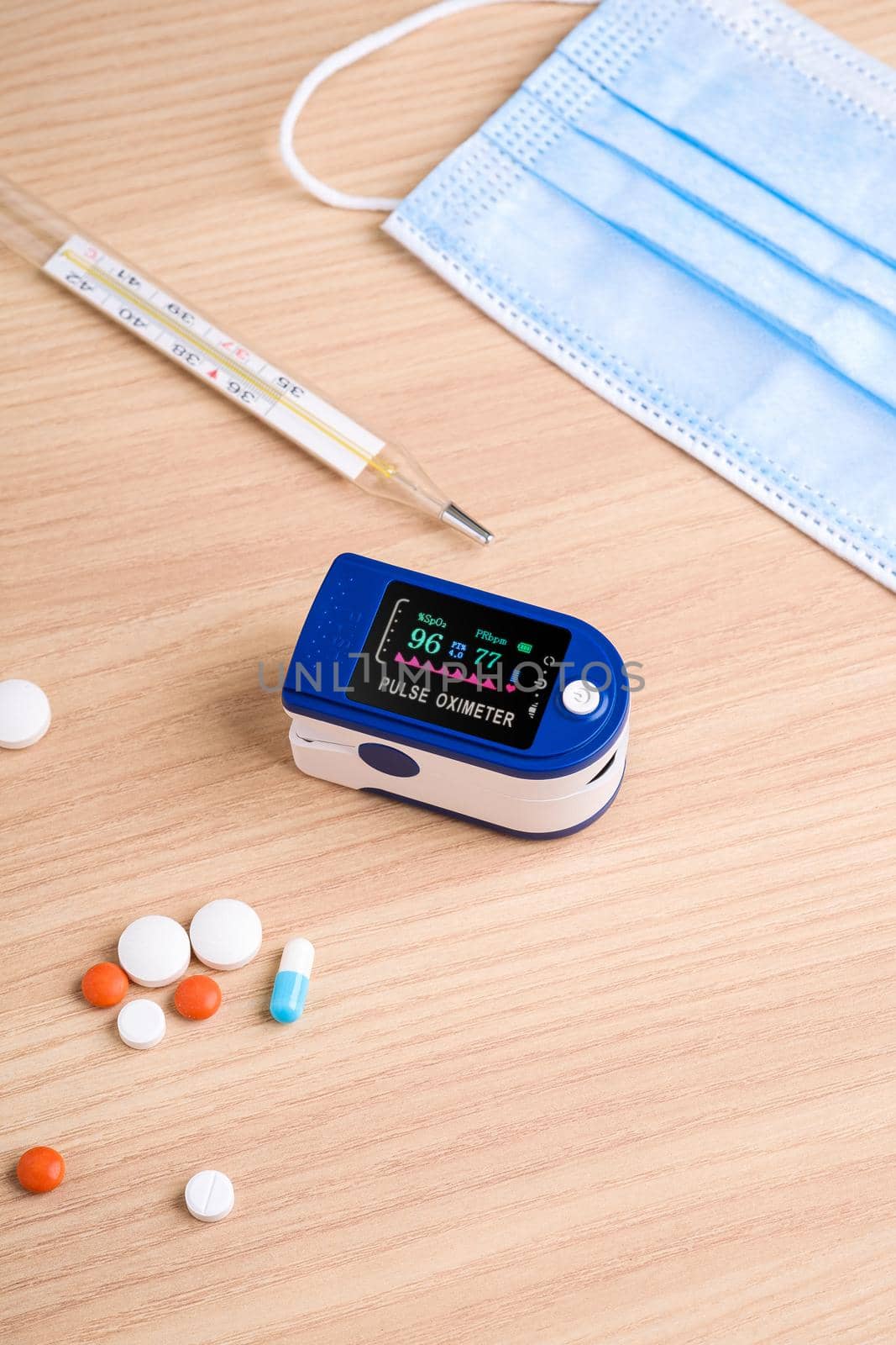 Pulse oximeter device near to pills, thermometer and medical mask, healthcare monitoring concept