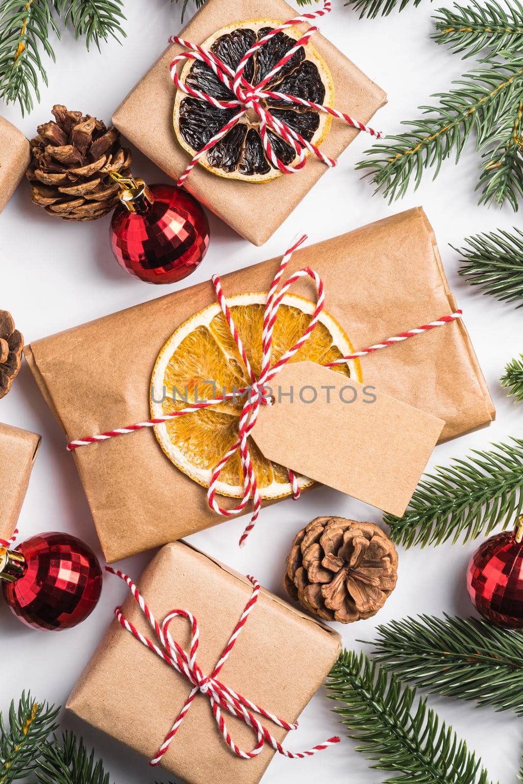 Christmas holidays zero waste paper gifts wrapping with tag, baubles, dried fruit and fir branches by Frostroomhead