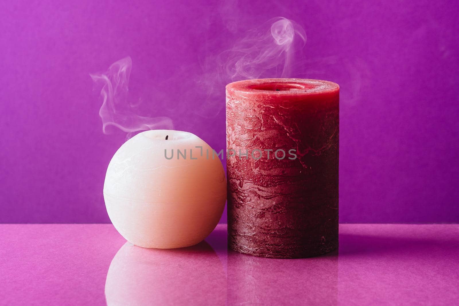 Red and white candles with smoke on purple background