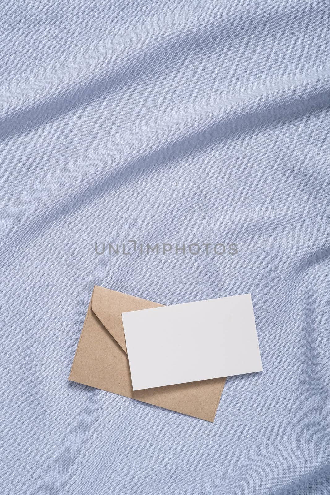 White blank paper card and envelope mockup on blue neutral colored textile