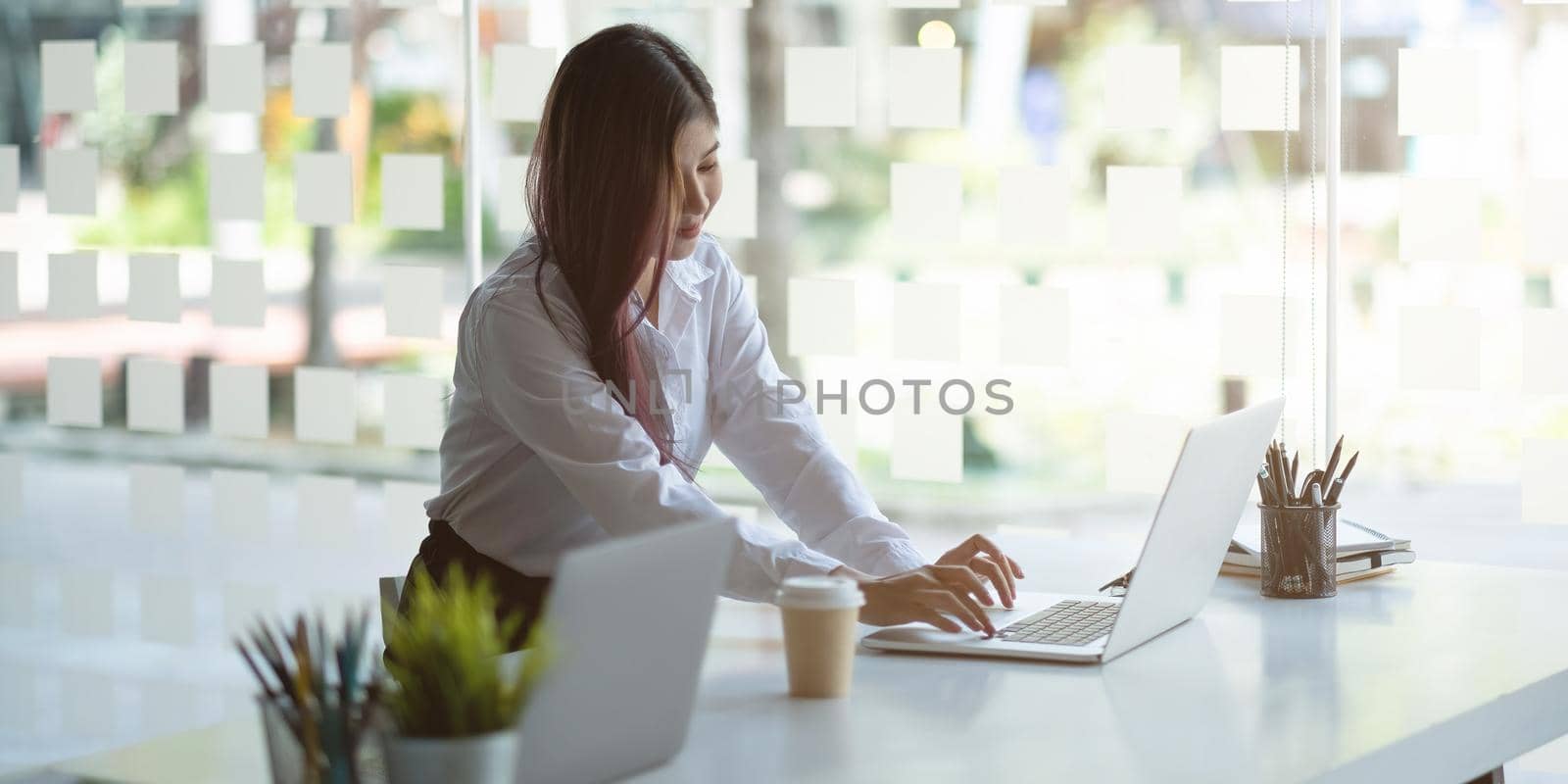 Businesswoman working on computer at table in office, Banner design by nateemee