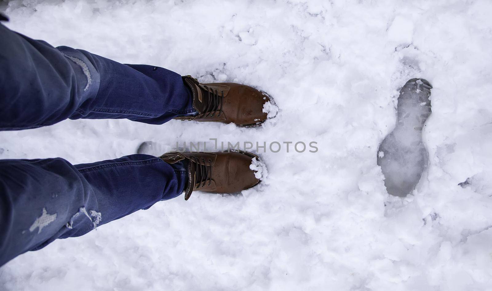 Detail of men's boots on a snowy day in winter, cold and ice
