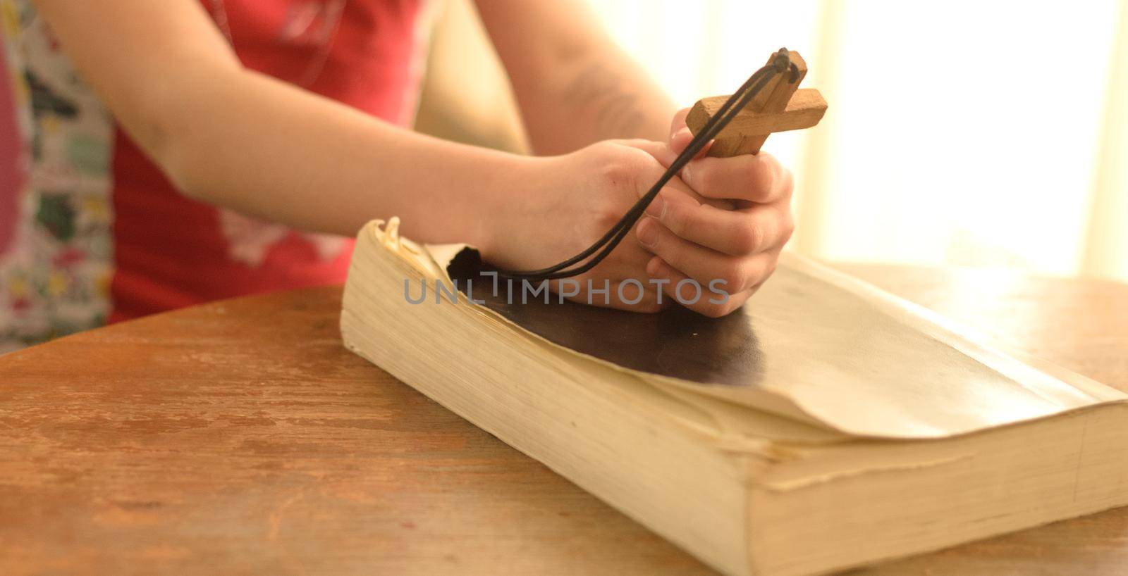 teenager girl praying to God holding a wooden cross,focus on cross.Concept of faith,hope and love.Christian Banner card.
