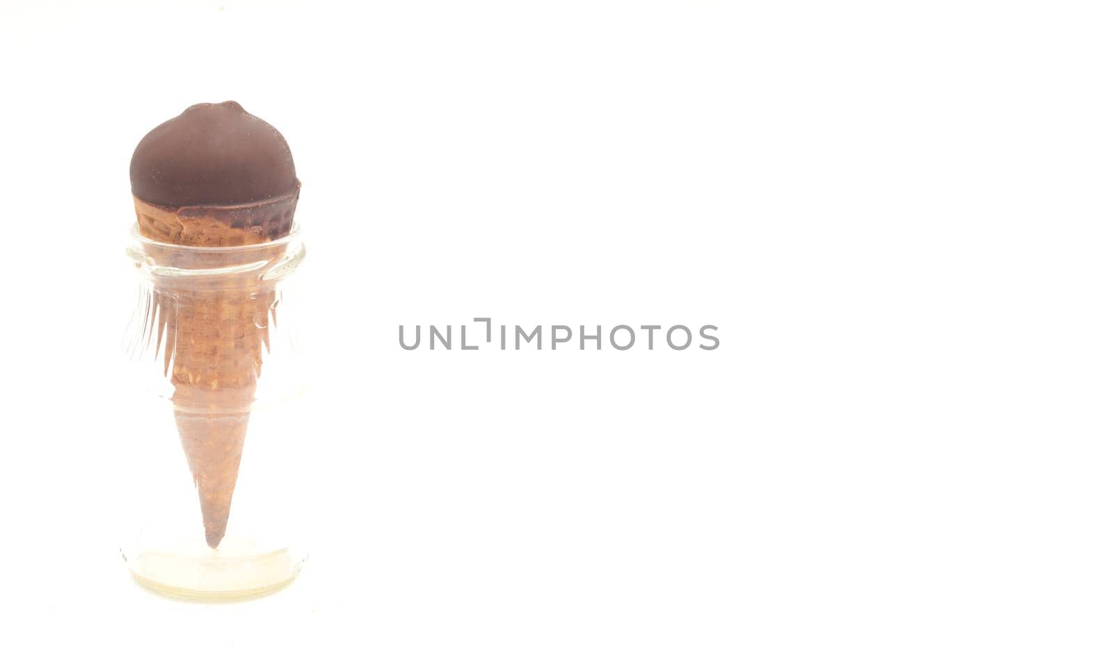 Chocolate ice-cream cone in small glass bottle on white background, copyspace. 