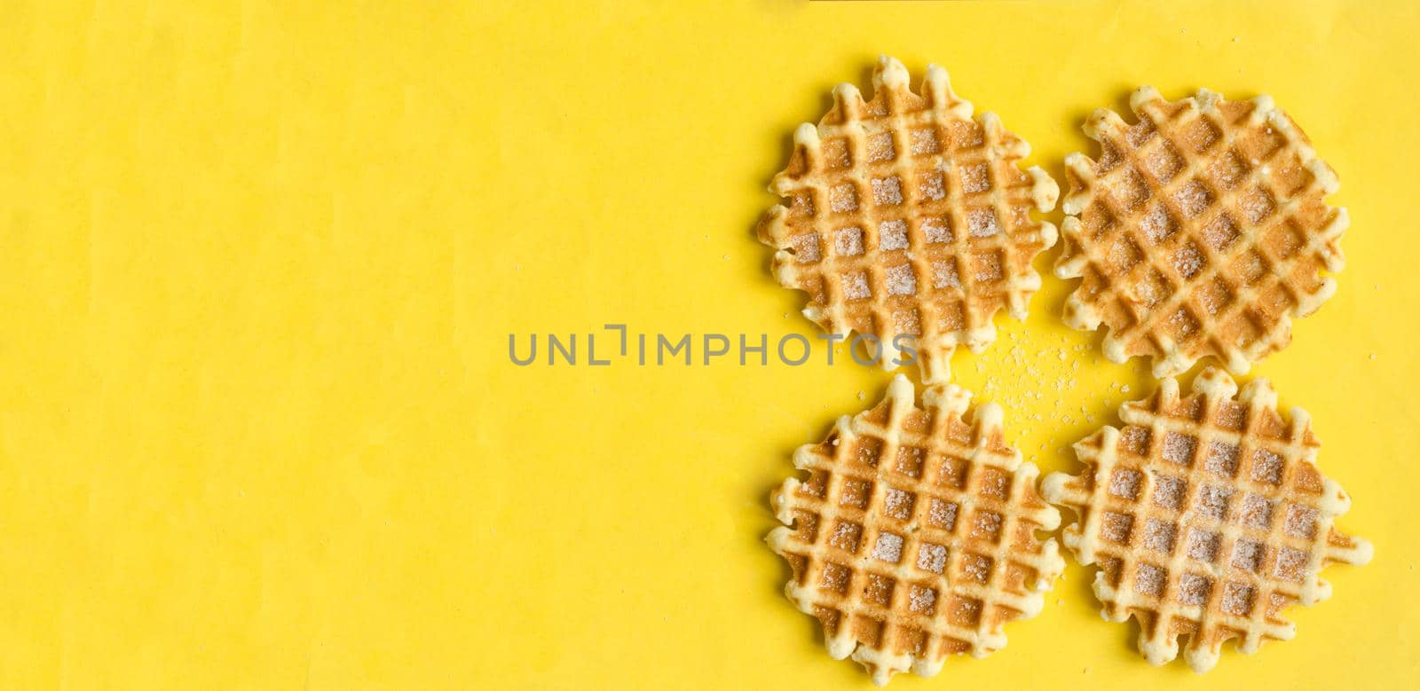 Top view, four sugar belgium waffles on yellow background, copyspace.Sweet dessert. by andre_dechapelle